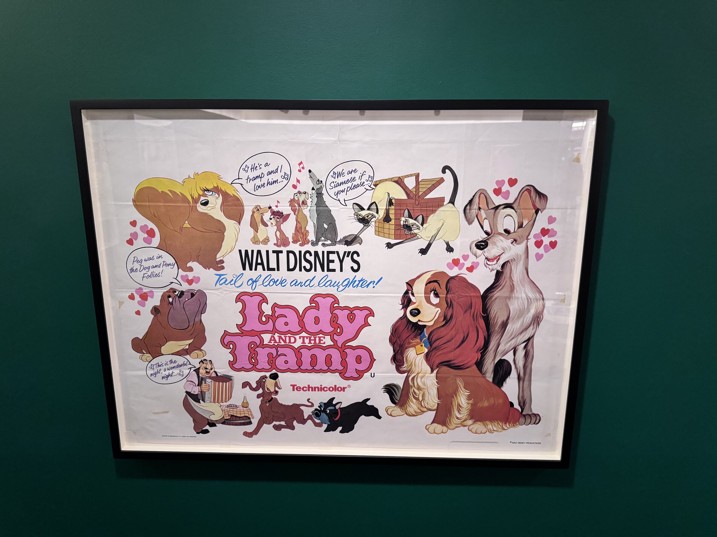 A framed English poster for Walt Disney's Lady and the Tramp hanging on a dark green wall in the Film Posters room of Awaking Beauty
