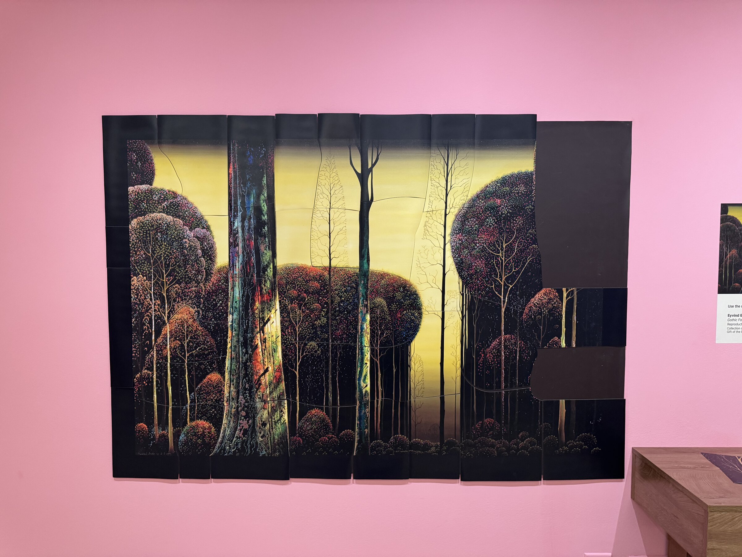 A wall-size magnetic puzzle of Eyvind Earle's 1979 painting Gothic Forest, tall trees against a yellow sky, with pieces missing