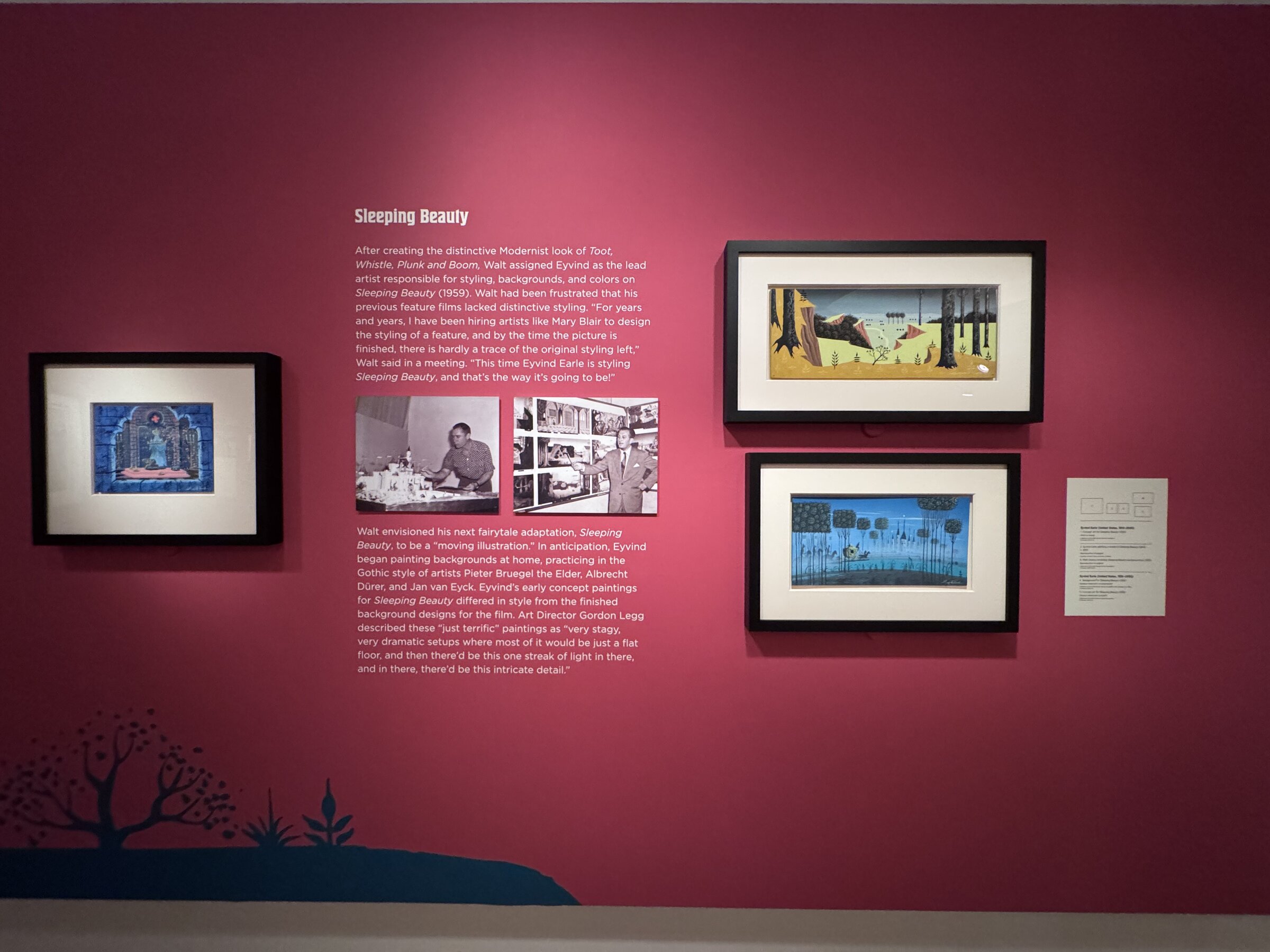 The Sleeping Beauty section of Awaking Beauty, with wall text, archival photos of Eyvind Earle and framed concept art on a deep pink wall