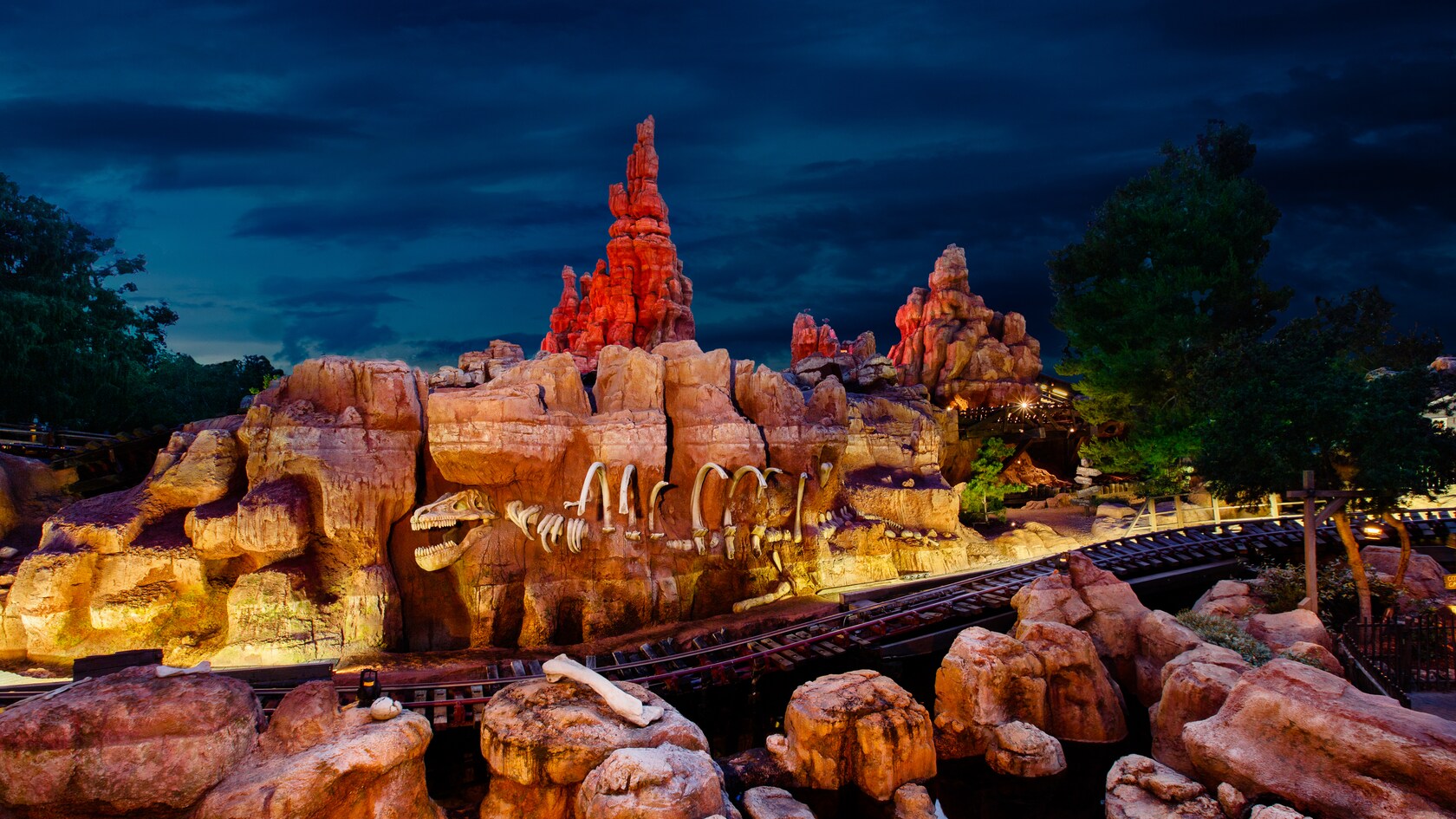 Big Thunder Mountain Railroad at Disneyland lit up at night under a dark sky