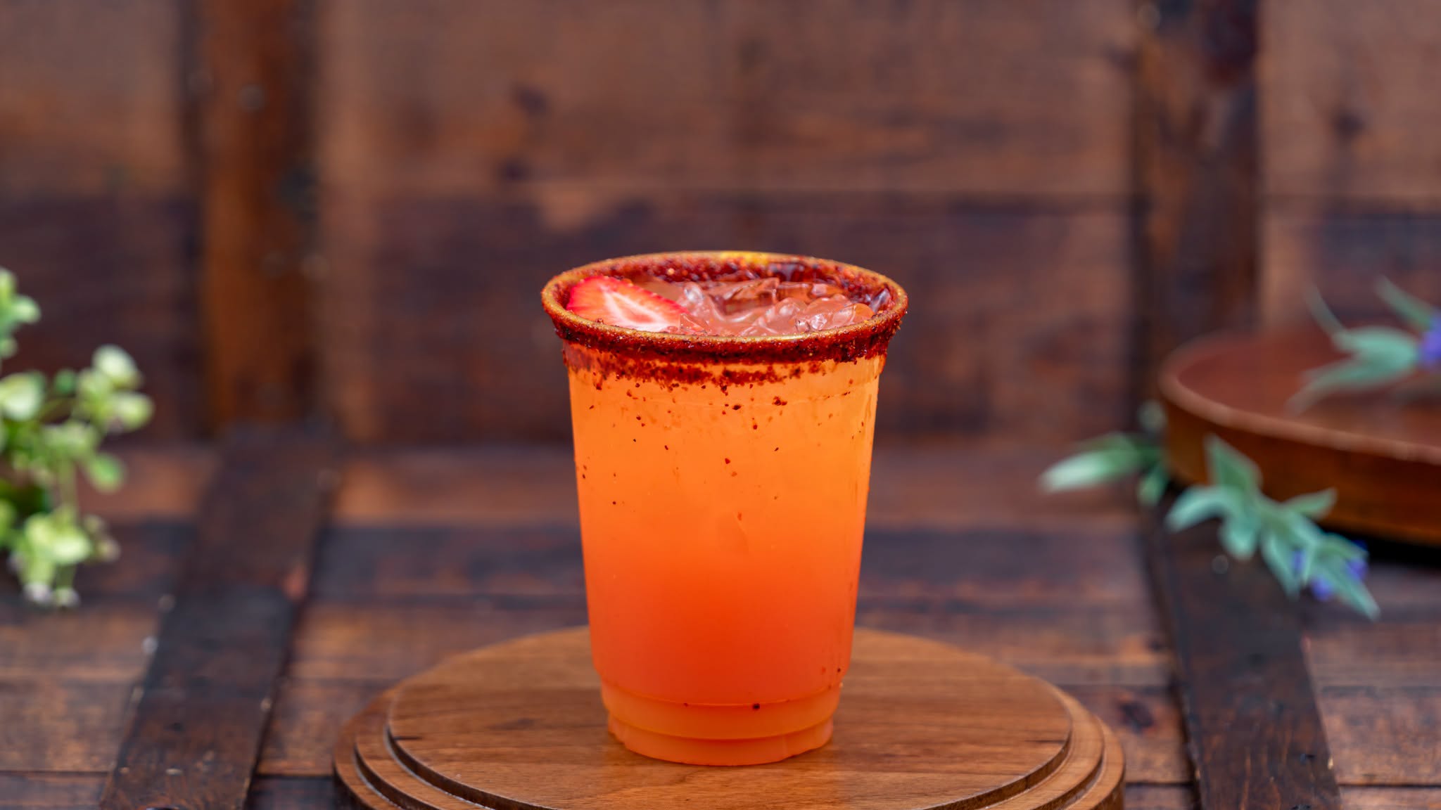 Strawberry-Mango Margarita, an orange drink over ice with a chile-lime rim and a strawberry slice on top