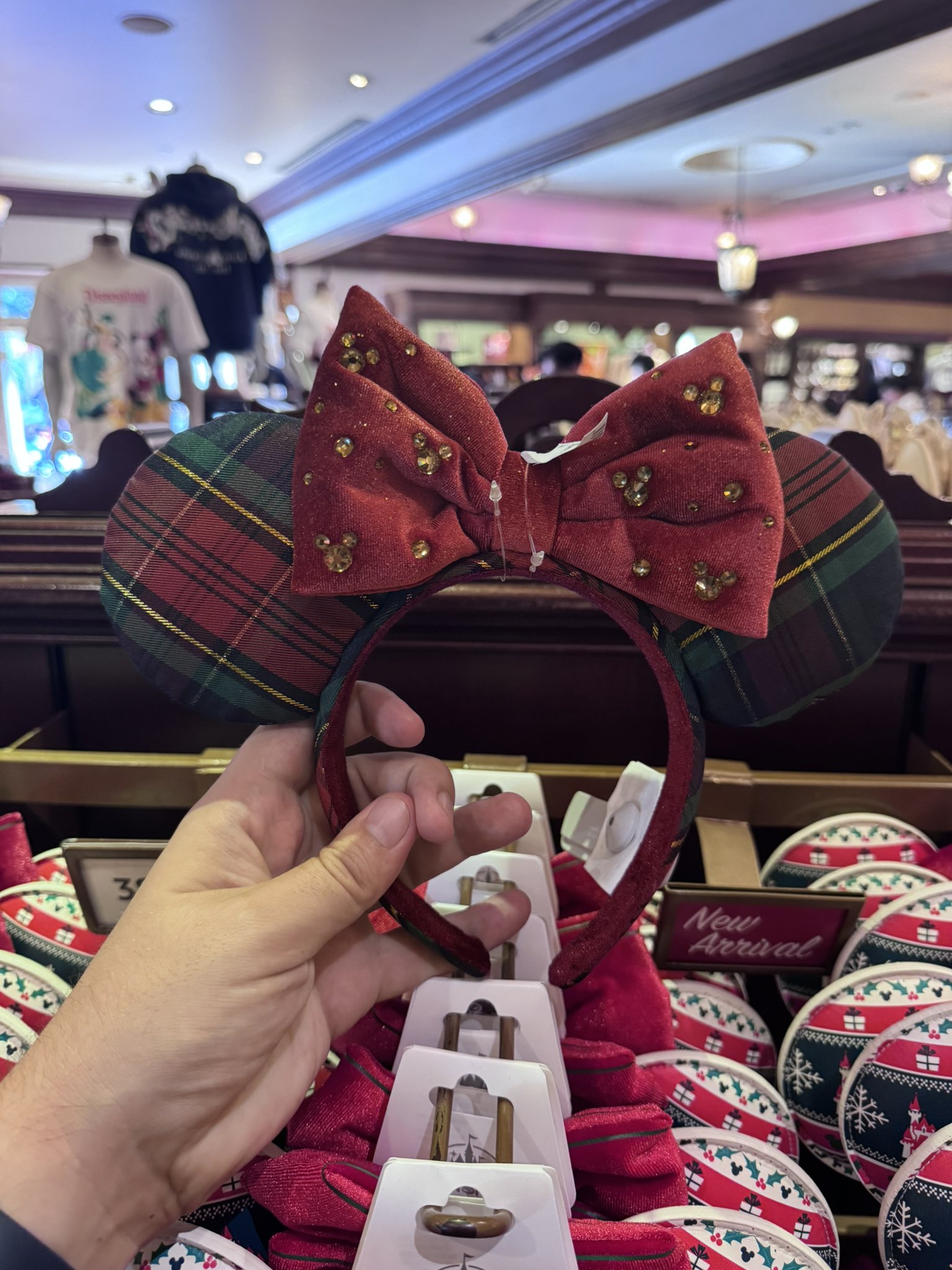 Green and red plaid Christmas Minnie ears with a red bow dotted with gold Mickey heads at the Emporium at Disneyland