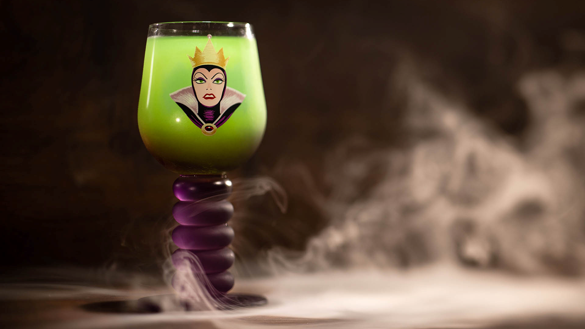 The Peddler's Disguise, a green drink in a goblet printed with the Evil Queen on a purple stem, with smoke around its base