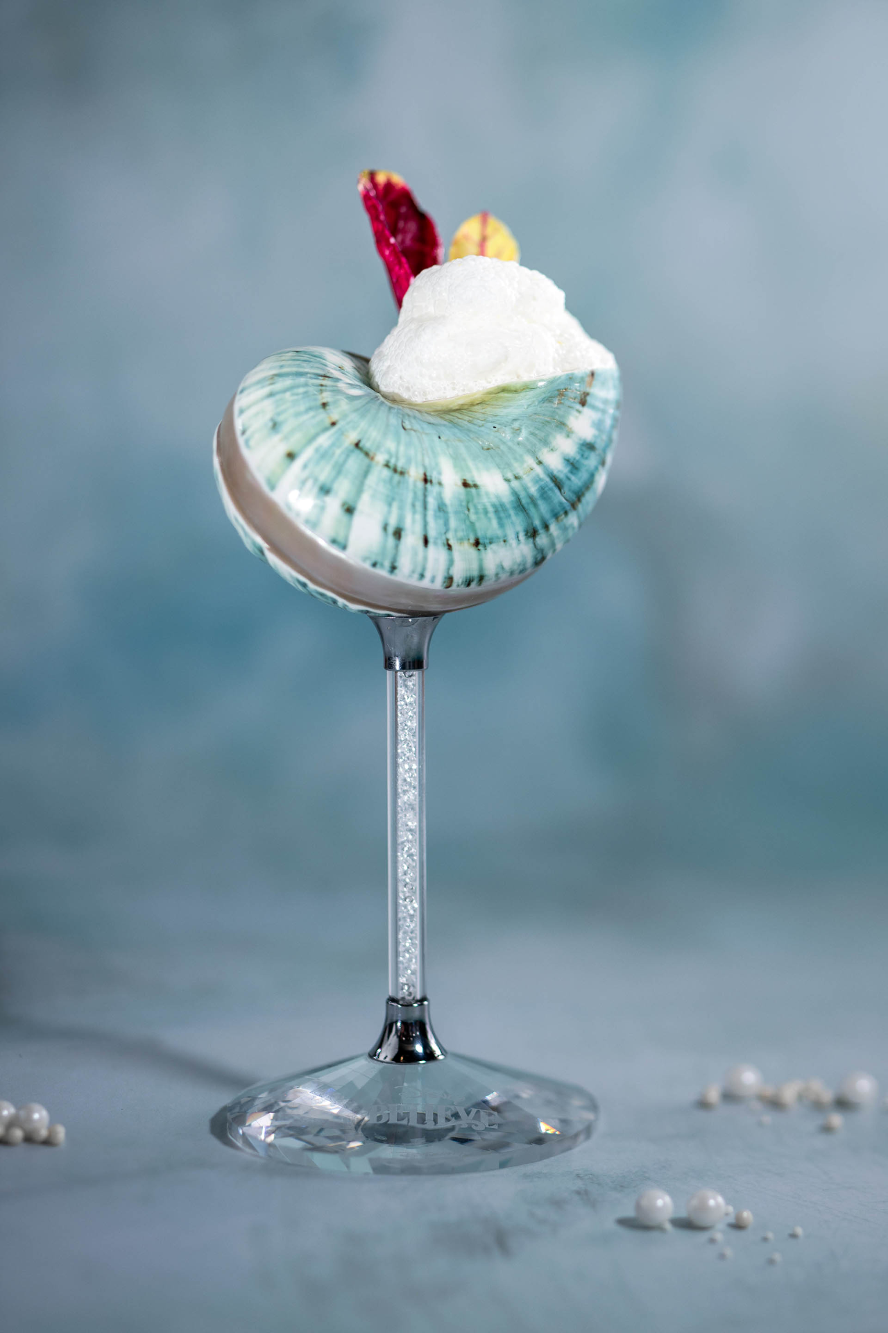 The Sea Salt Martini in a seashell-shaped glass topped with foam, coming to Sea Notes on the Disney Believe
