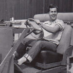A young Bob Gurr smiling at the wheel of a vehicle mockup