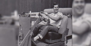 A young Bob Gurr smiling at the wheel of a vehicle mockup