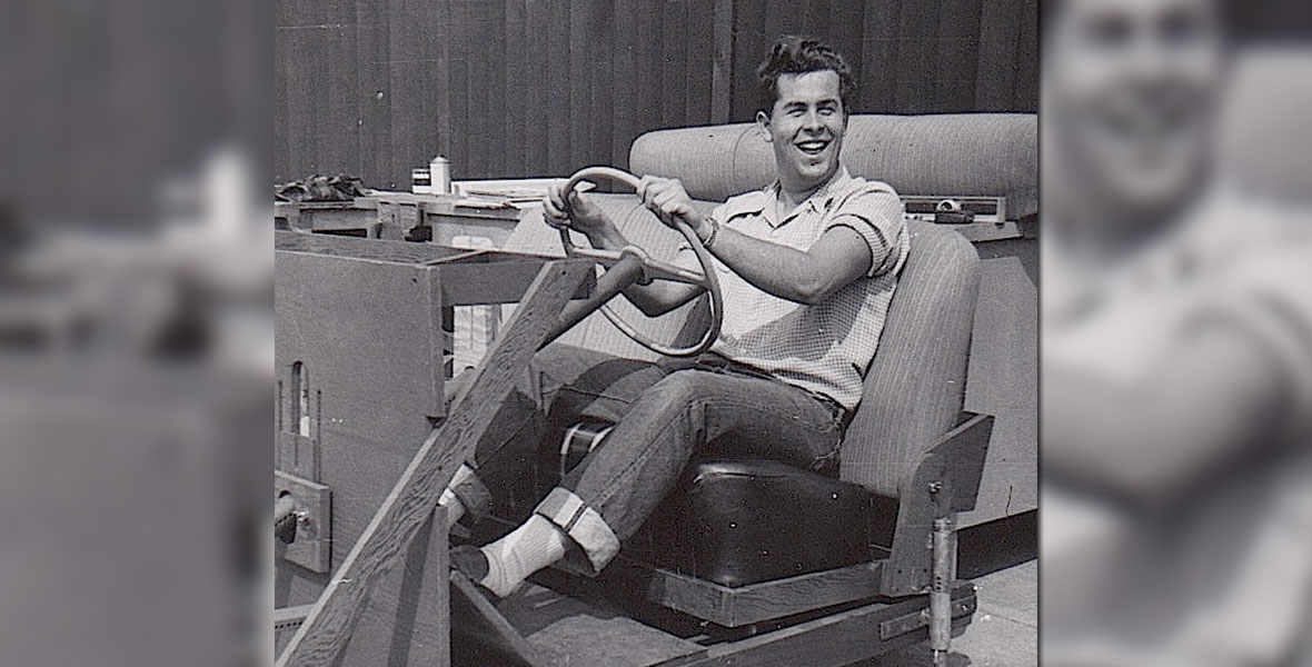 A young Bob Gurr smiling at the wheel of a vehicle mockup