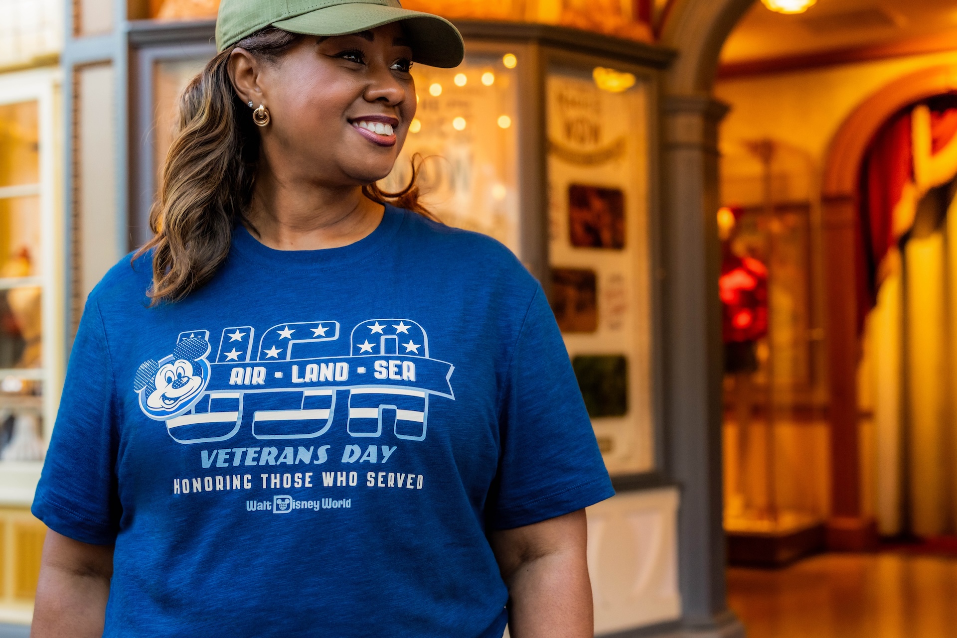 Guest wearing the blue 2026 Disney Veterans Day T-shirt and a green cap