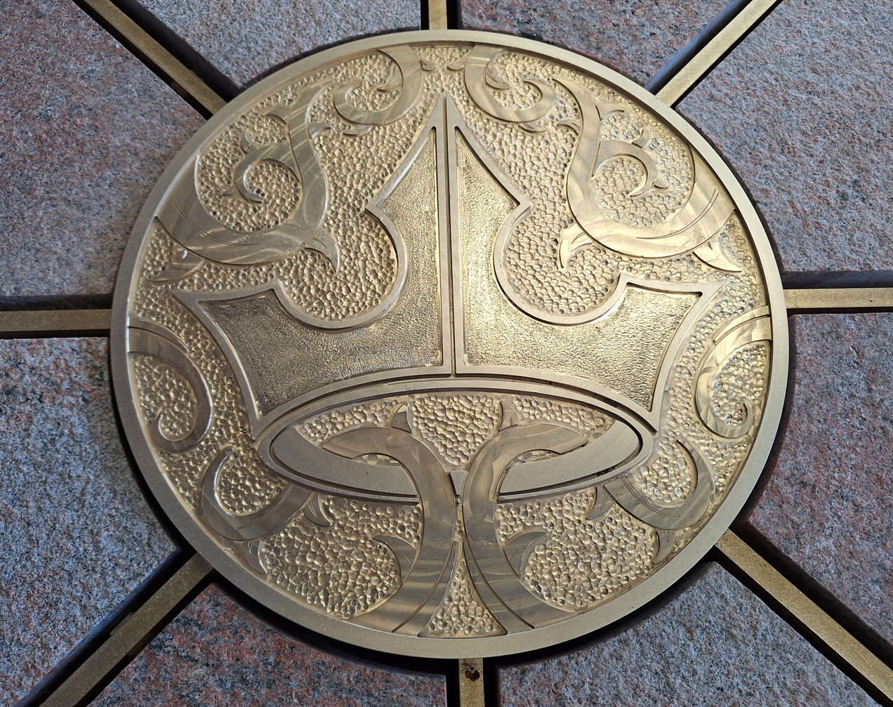 Brass medallion of Aurora's crown surrounded by thorns at the center of the Sleeping Beauty Castle bridge compass rose