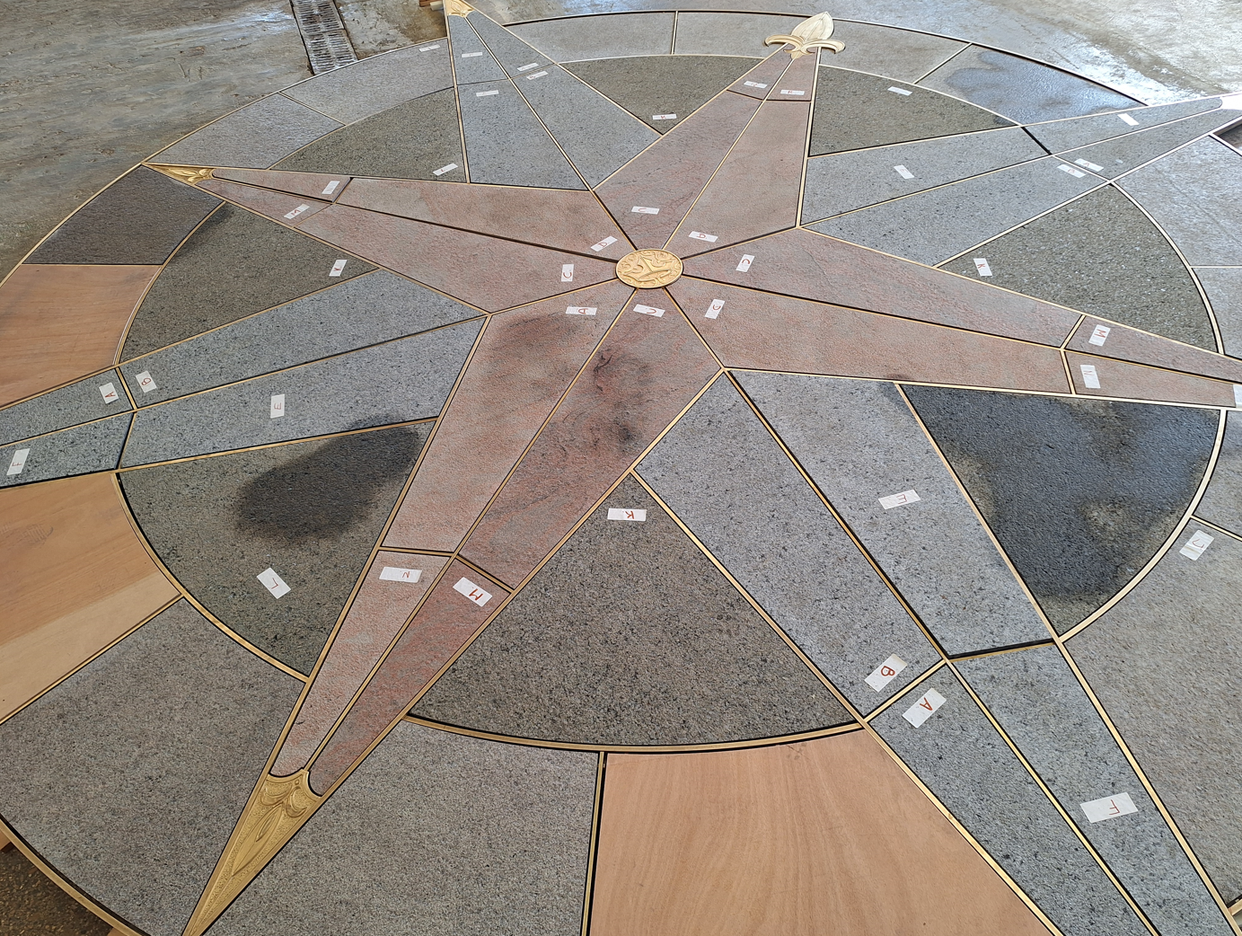 The new compass rose on the Sleeping Beauty Castle bridge at Disneyland Paris, with red, blue and green stone points and brass inlays