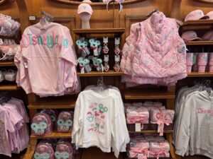 Pastel Holiday Collection display at Disneyland with a pink Spirit Jersey, puffer vest, white sweatshirt and gray hoodies