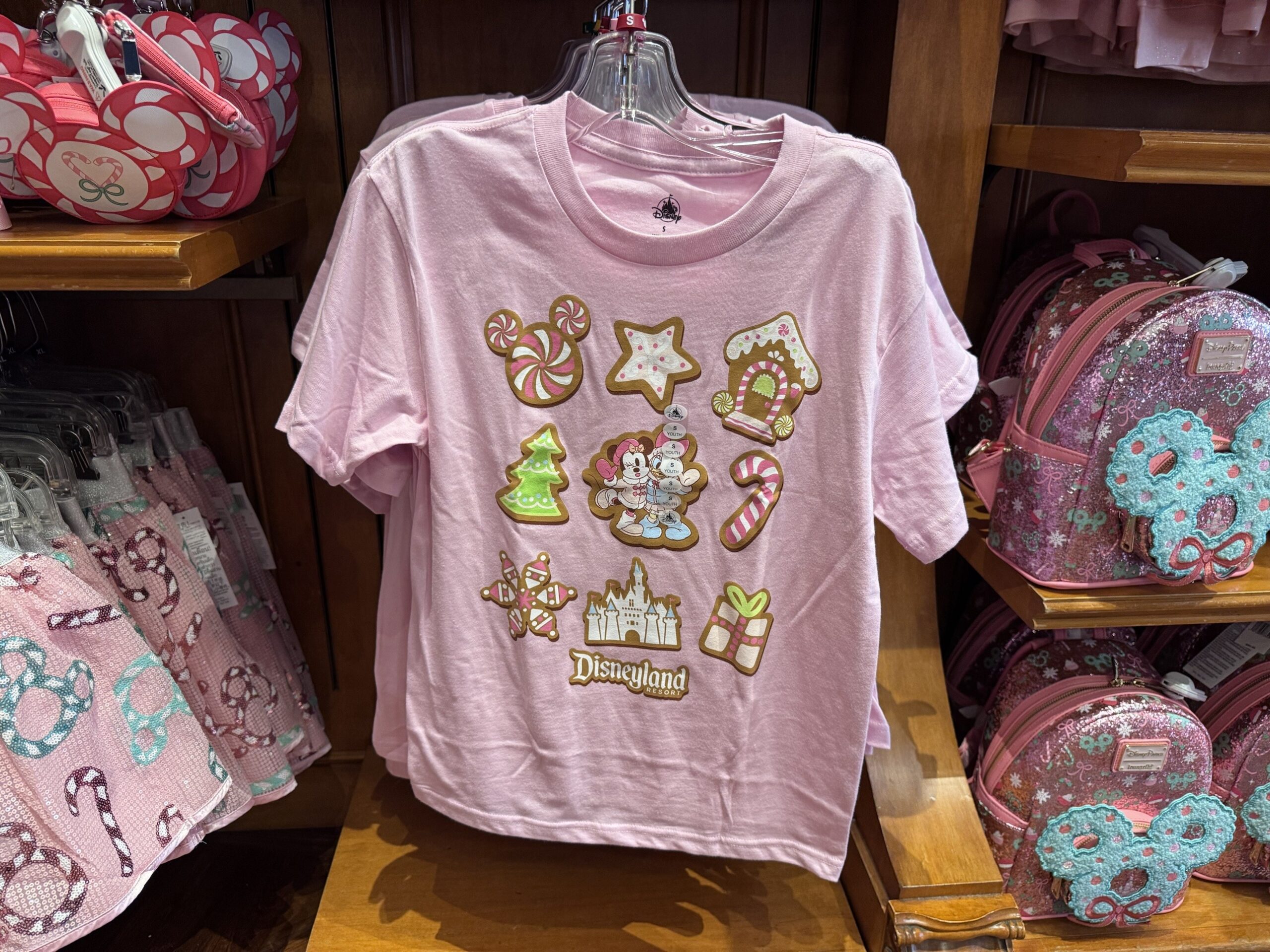 Pink youth tee printed with gingerbread cookies, Minnie and Daisy, the castle and a Disneyland Resort logo