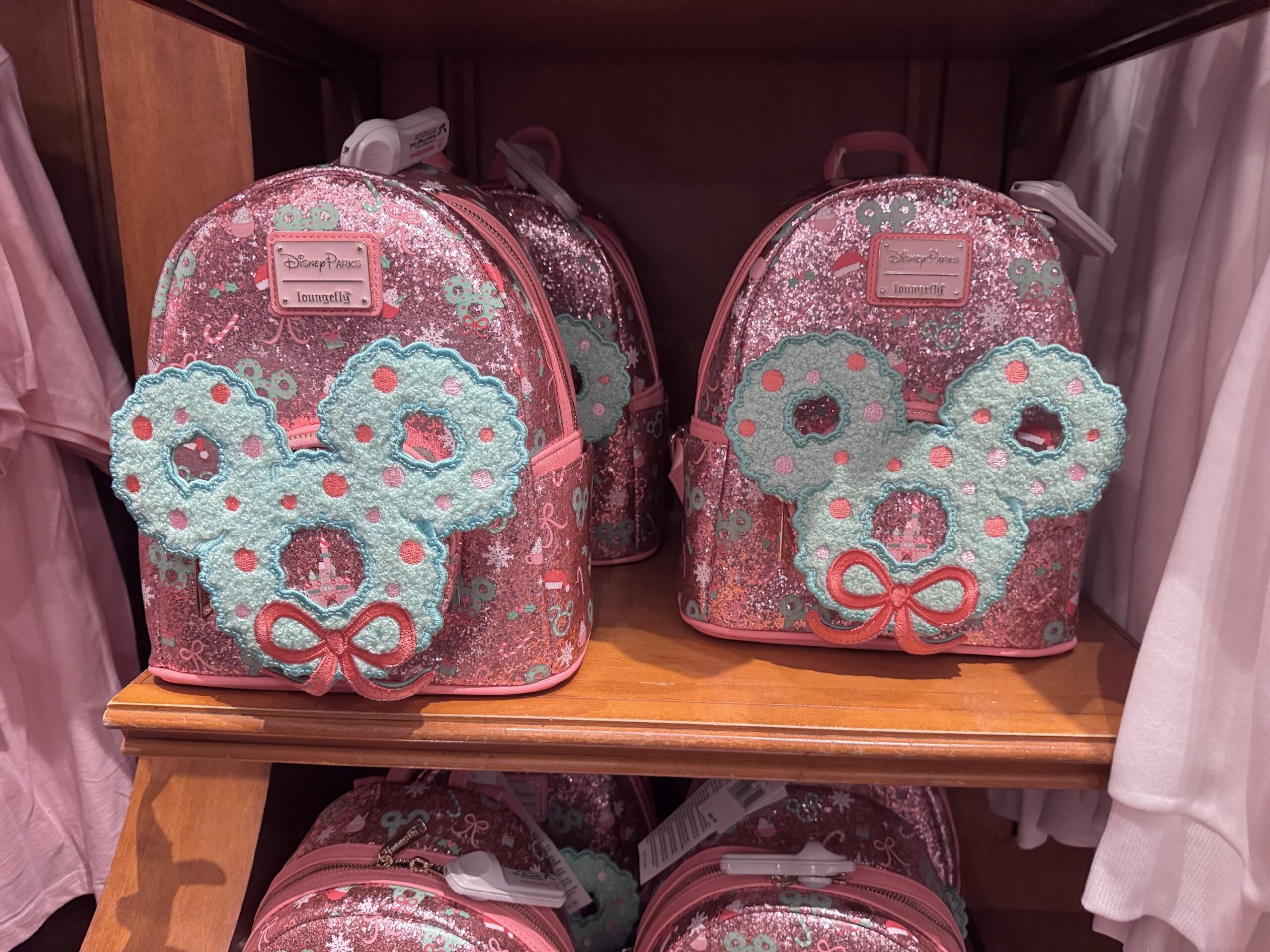 Pink glitter Disney Parks Loungefly mini backpacks with a fuzzy teal Mickey wreath and pink bow