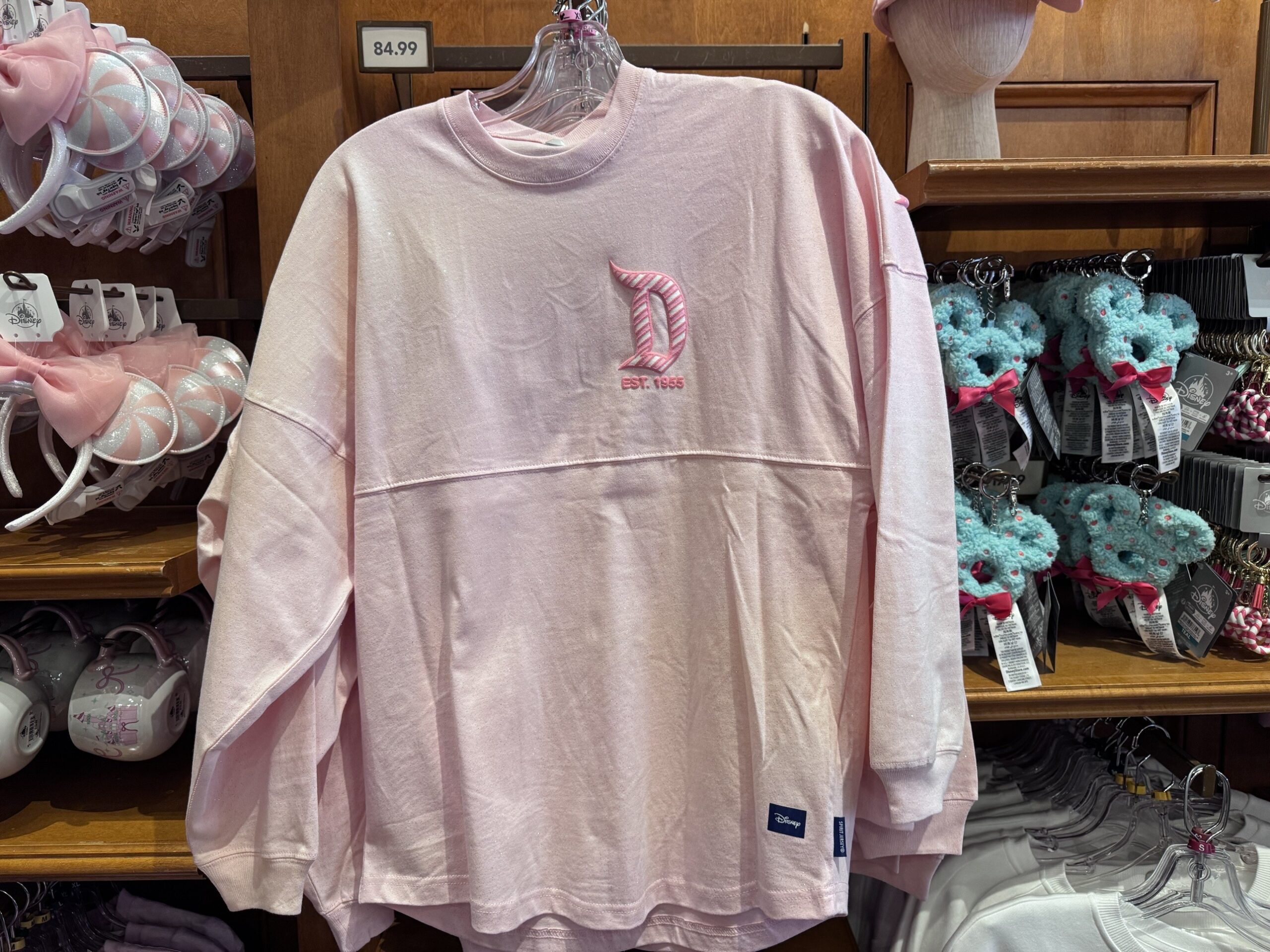 Pale pink long-sleeve top with a candy-striped Disneyland D and Est. 1955