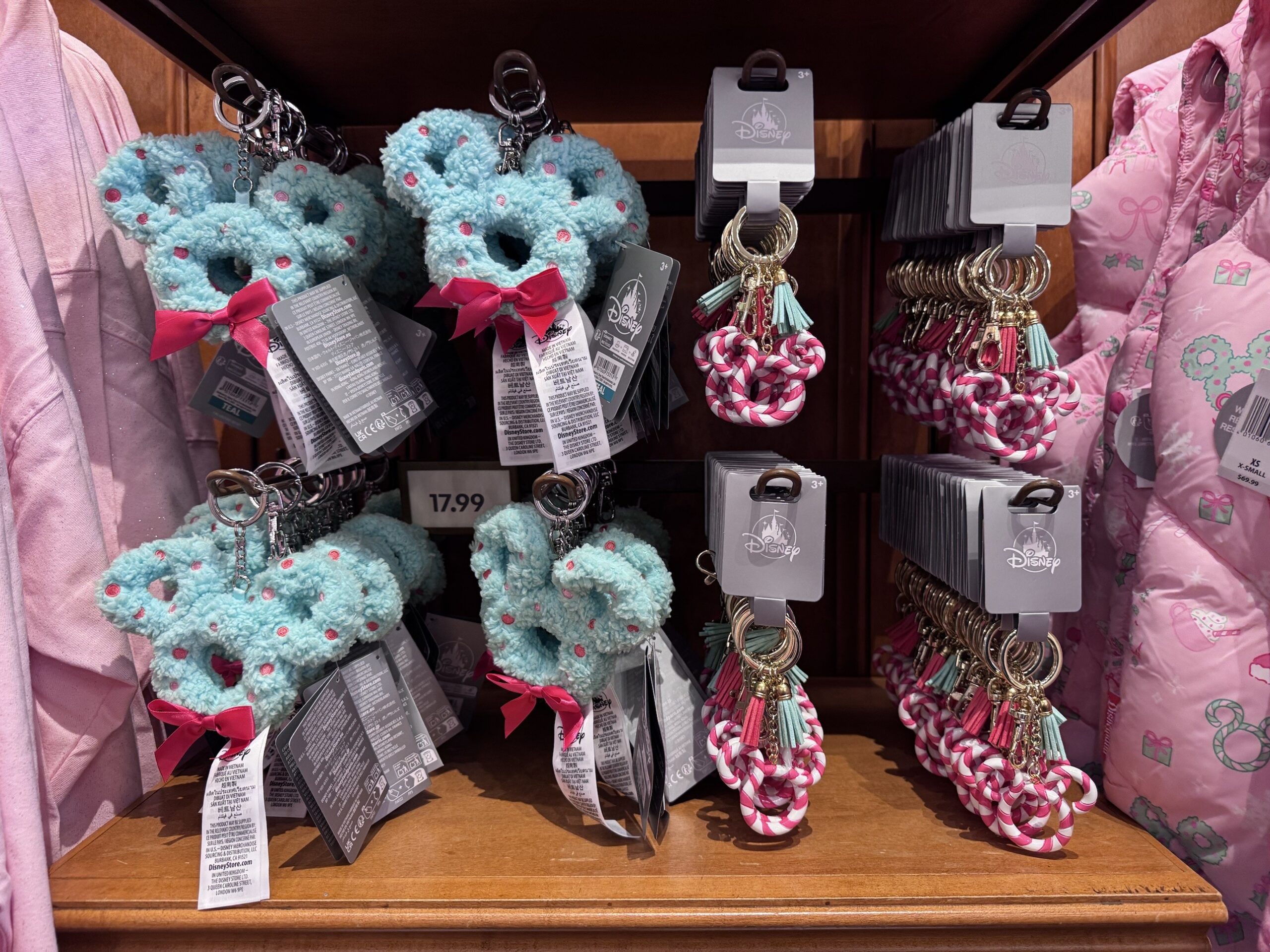 Fuzzy teal Mickey wreath bag charms with pink bows priced $17.99 next to candy cane Mickey keychains with tassels
