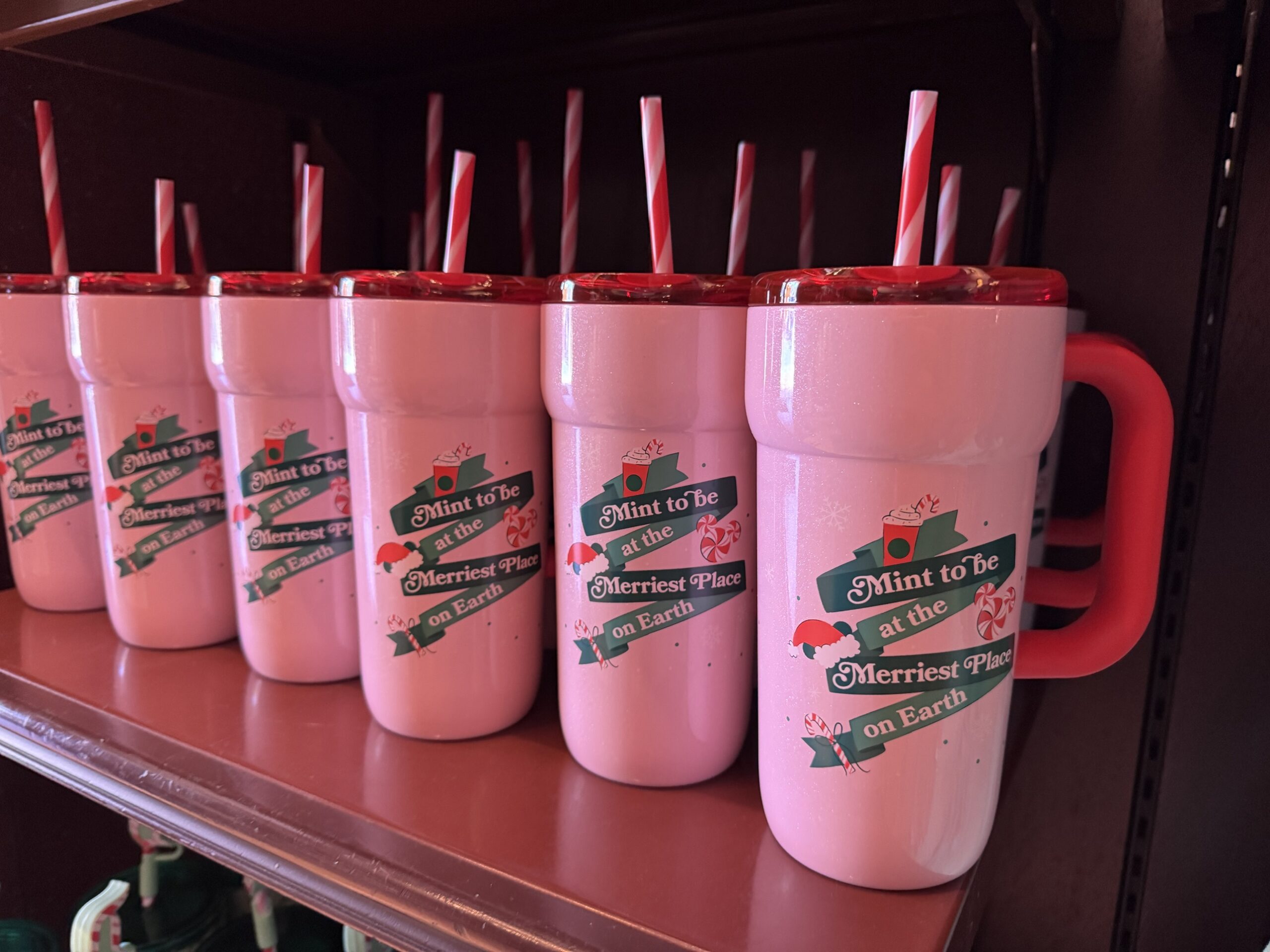 Pink Starbucks tumblers with red handle and striped straw reading Mint to be at the Merriest Place on Earth