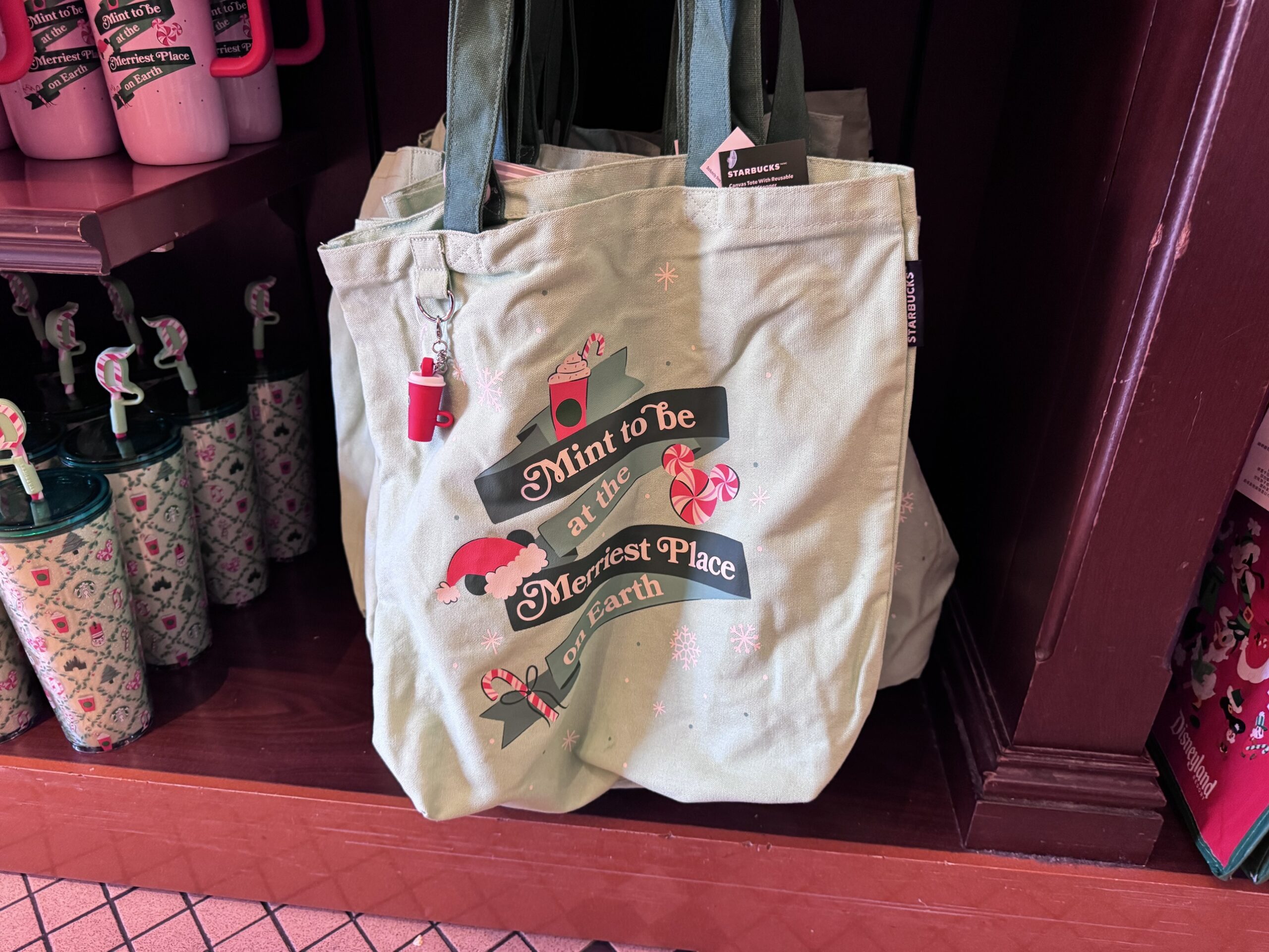 Mint green Starbucks canvas tote reading Mint to be at the Merriest Place on Earth with a mini red cup charm