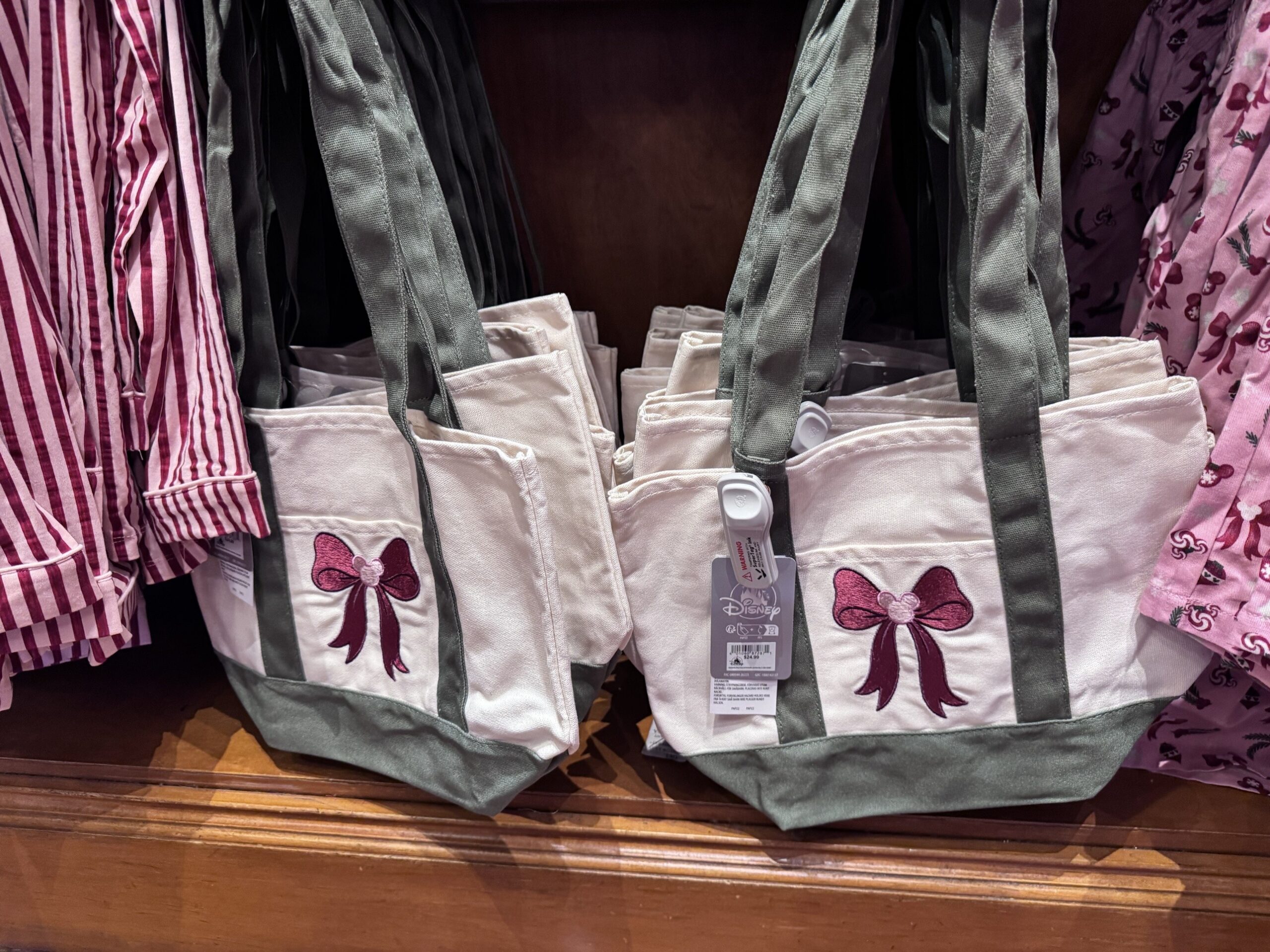 Cream canvas totes with sage handles and an embroidered burgundy bow with a pink Mickey icon, tagged $24.99