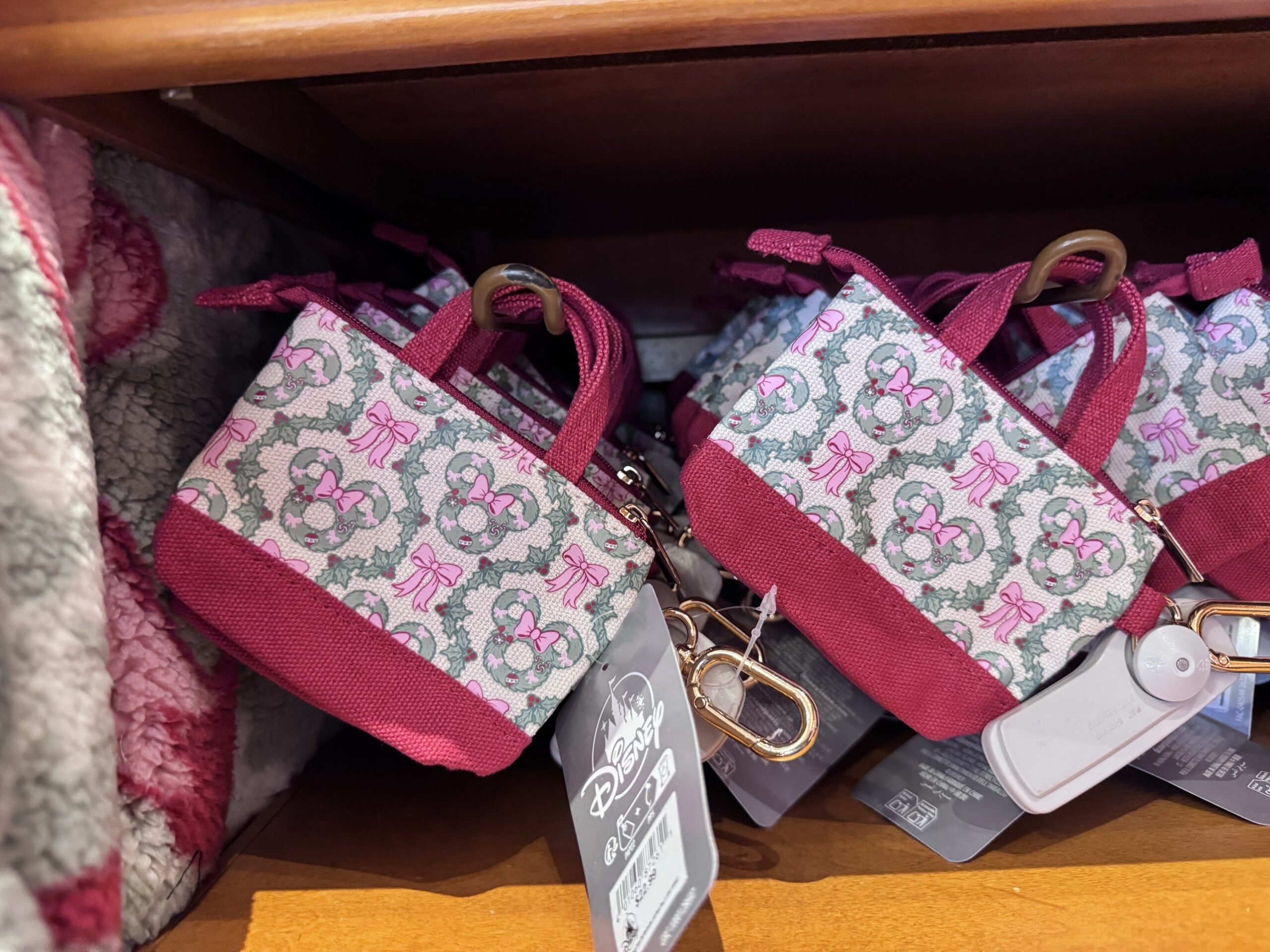 Mini canvas tote bag charms with a burgundy base, printed with Minnie holly wreaths and pink bows
