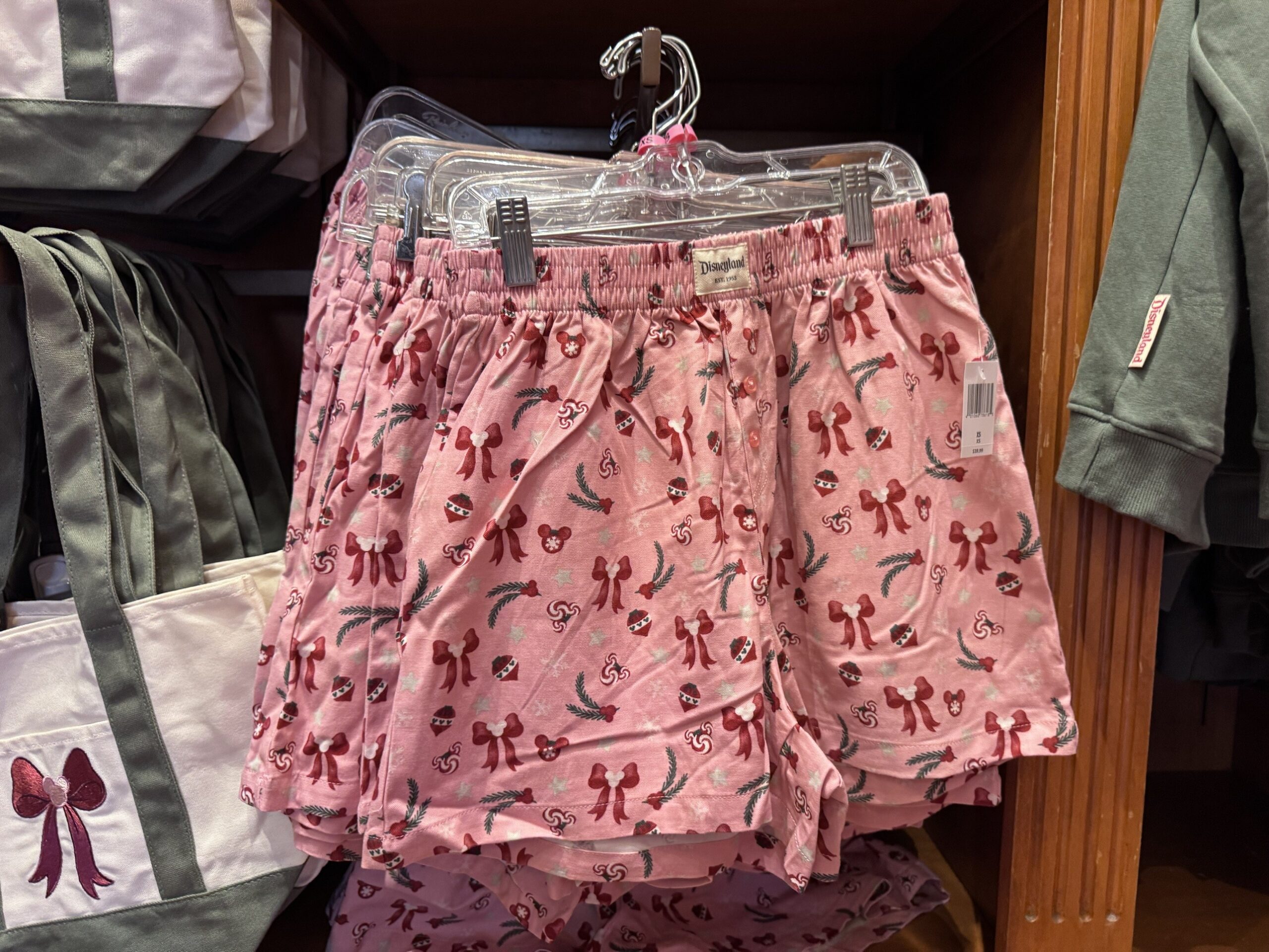 Pink Disneyland shorts printed with burgundy bows, ornaments, peppermints and pine sprigs
