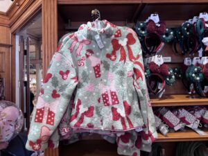 Sage sherpa jacket with red and pink bows, gifts and Mickey icons next to holly wreath Minnie ears