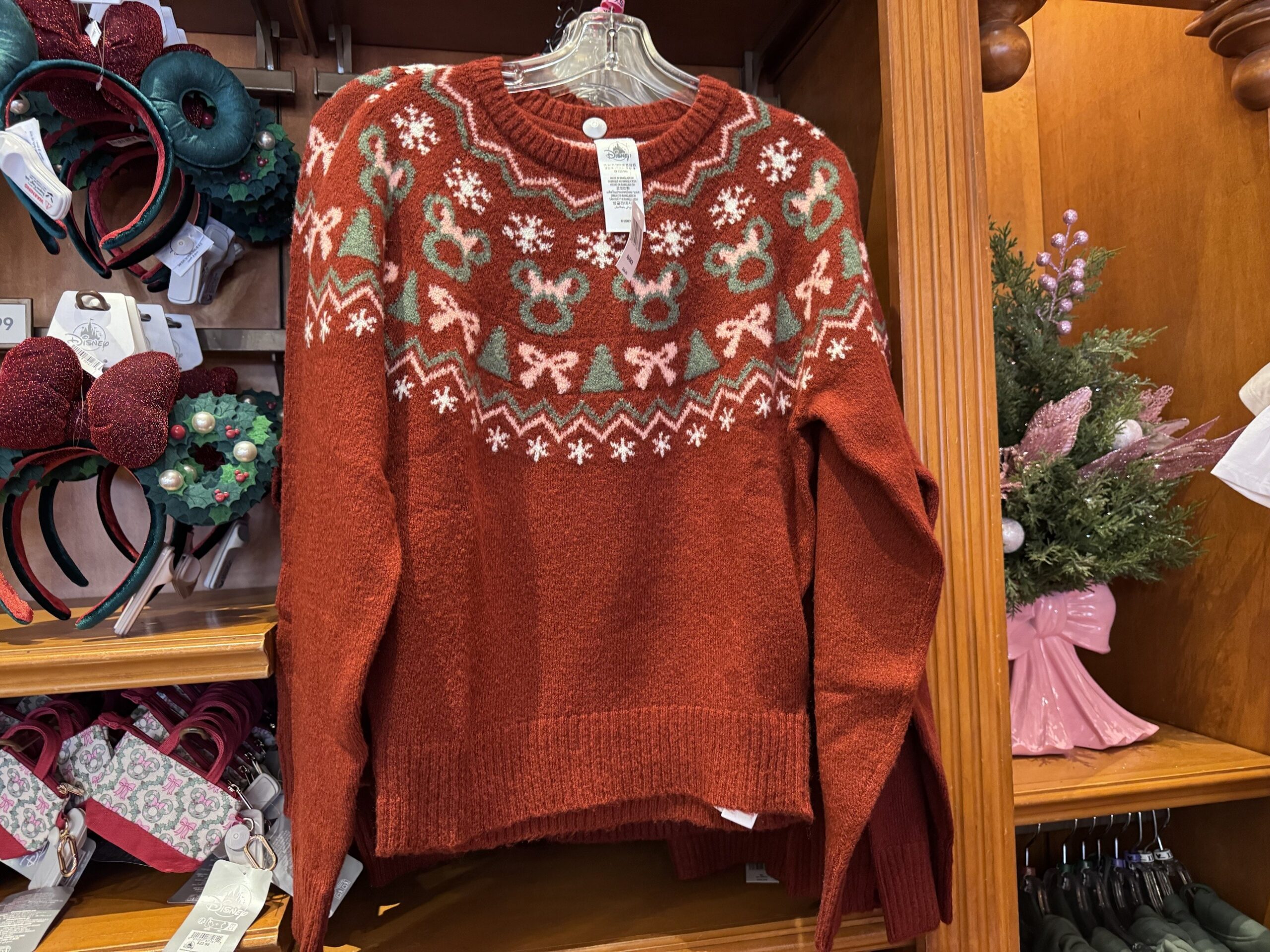 Rust red knit sweater with a yoke of Minnie wreaths, pink bows, trees and snowflakes
