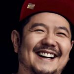 Eric Bauza smiling in a red cap