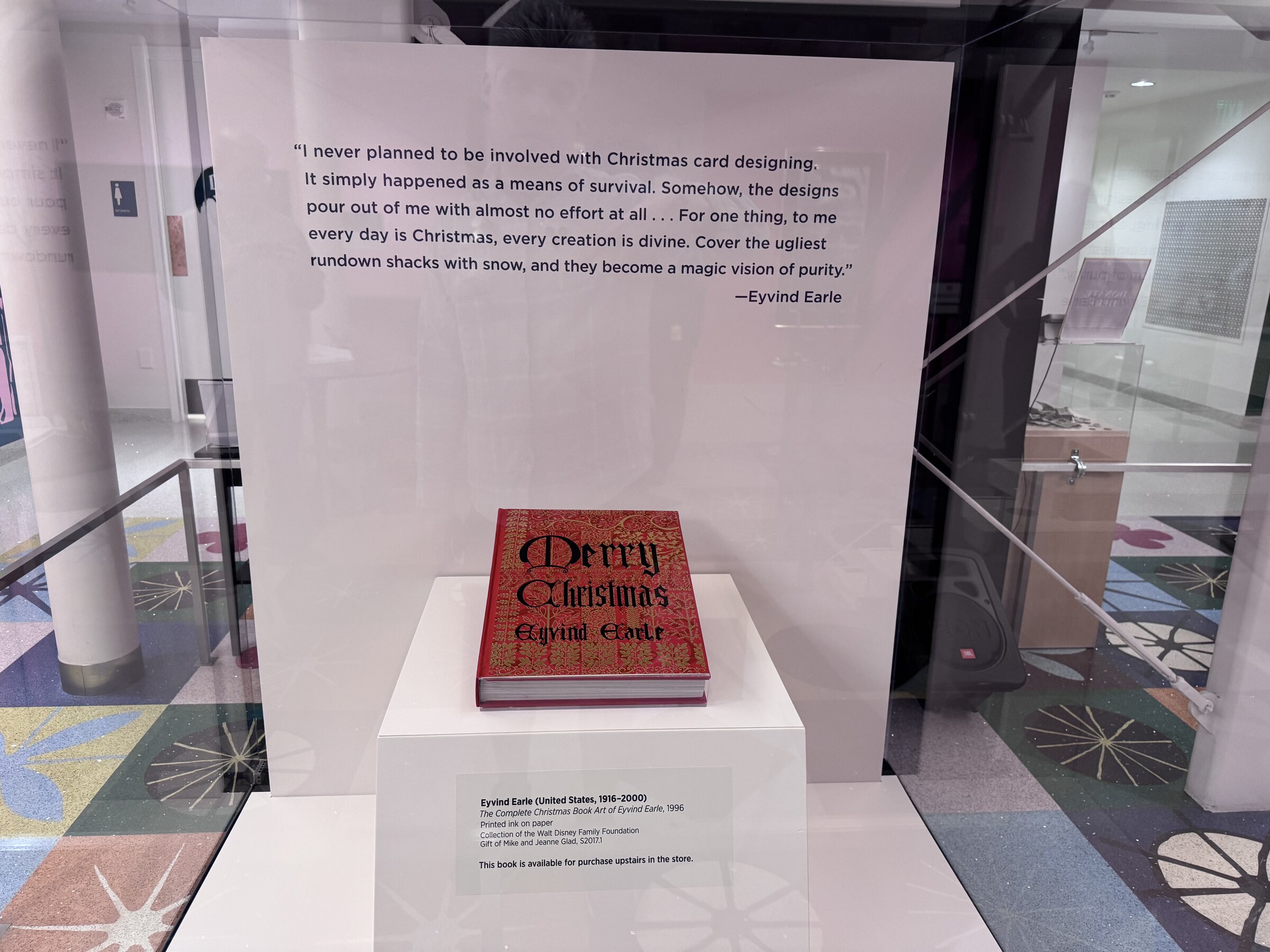 The Complete Christmas Book Art of Eyvind Earle in a display case beneath a printed quote from Earle about designing Christmas cards