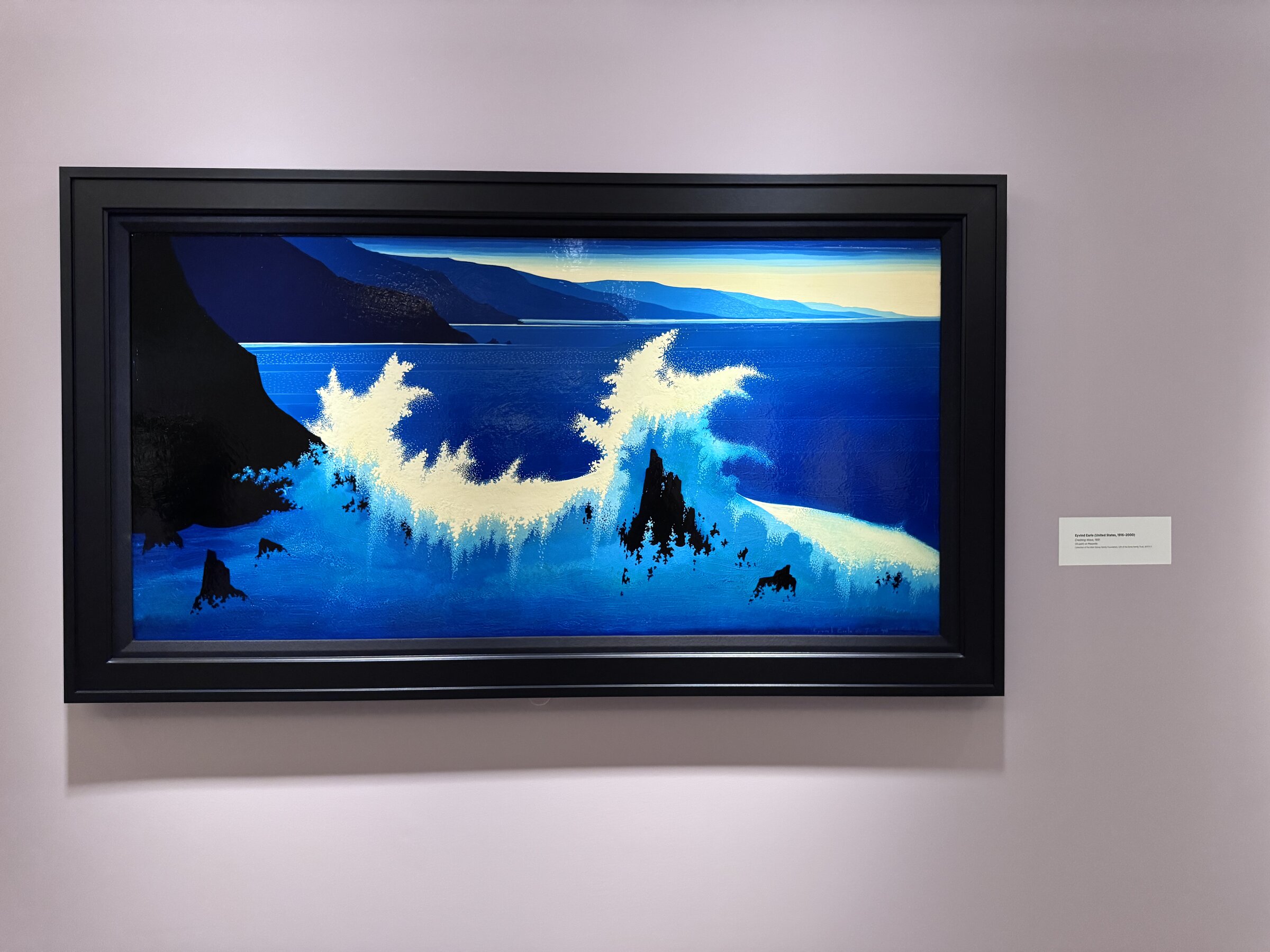 Eyvind Earle's Crashing Wave, a 1991 oil painting of white surf breaking against dark rocks on a deep blue coastline