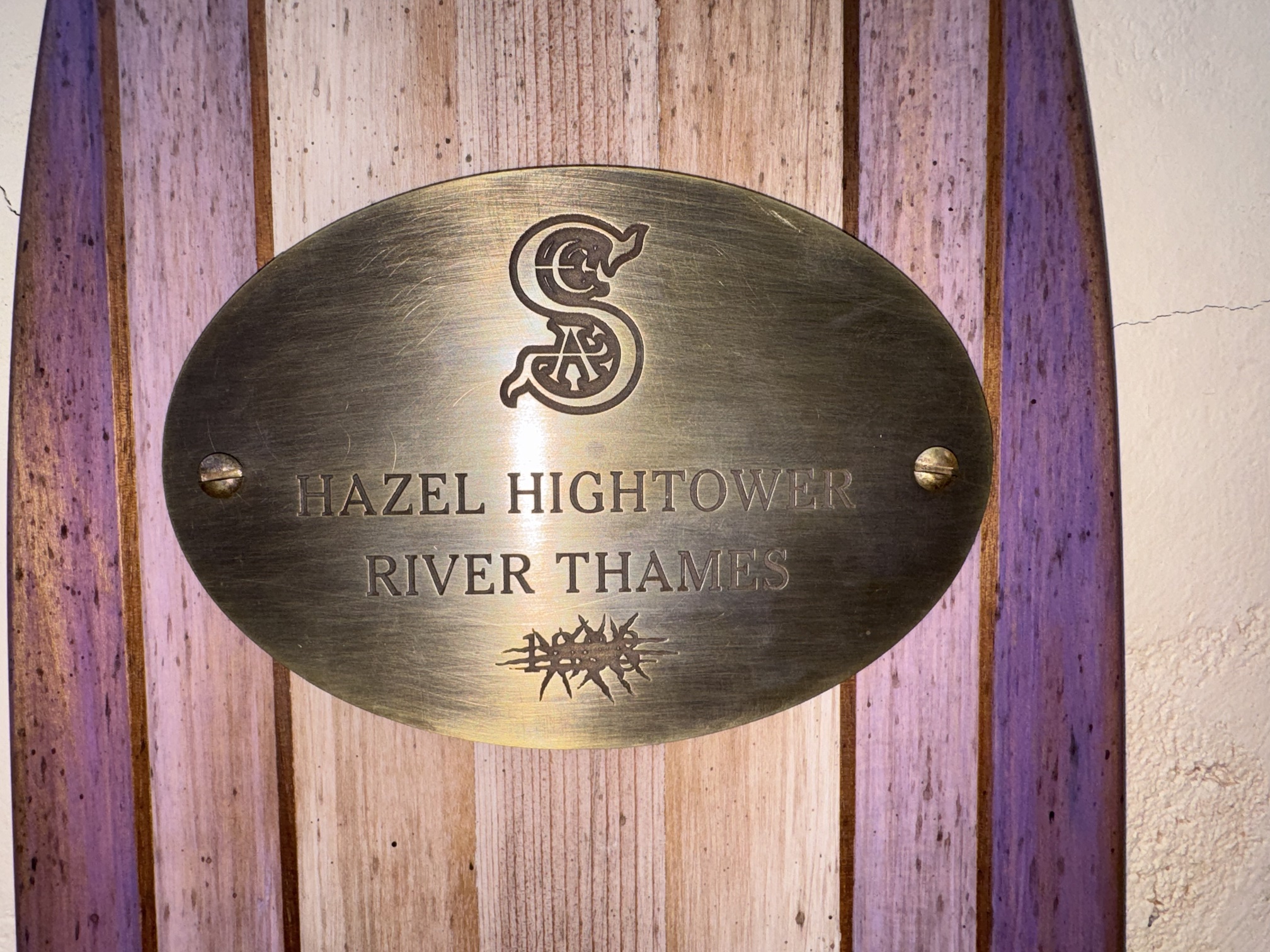 Brass S.E.A. plaque reading Hazel Hightower River Thames with a scratched-out year, below a mounted pocket watch
