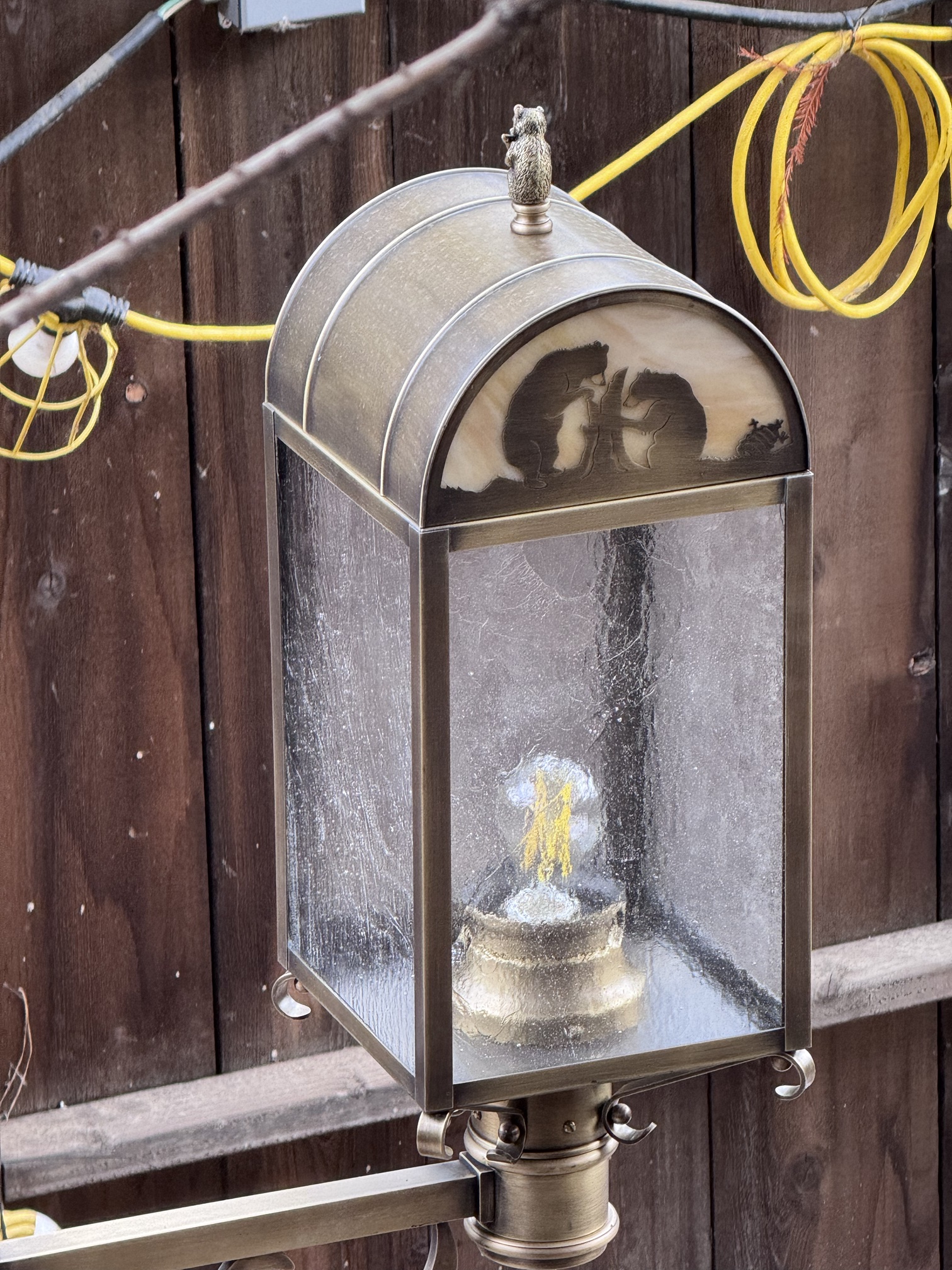 A bear finial tops a Hungry Bear Barbecue Jamboree lantern showing two bears and a tree