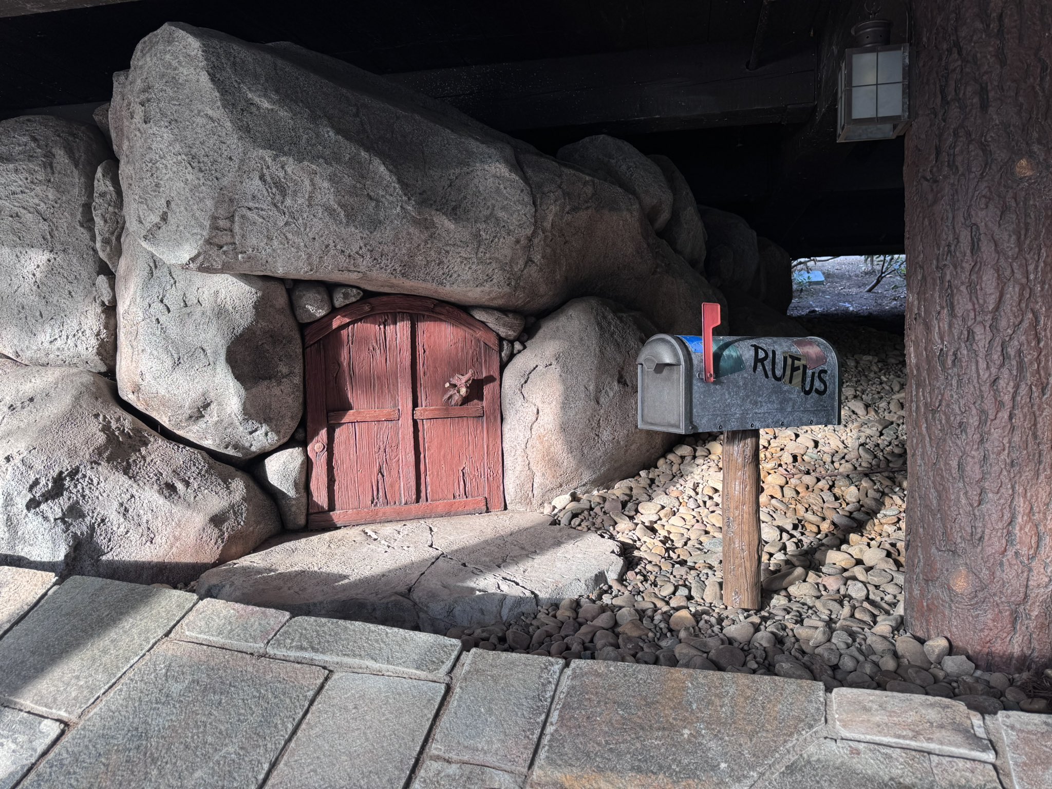 A small red door in the rocks with a Rufus mailbox in the new Hungry Bear Barbecue Jamboree seating area