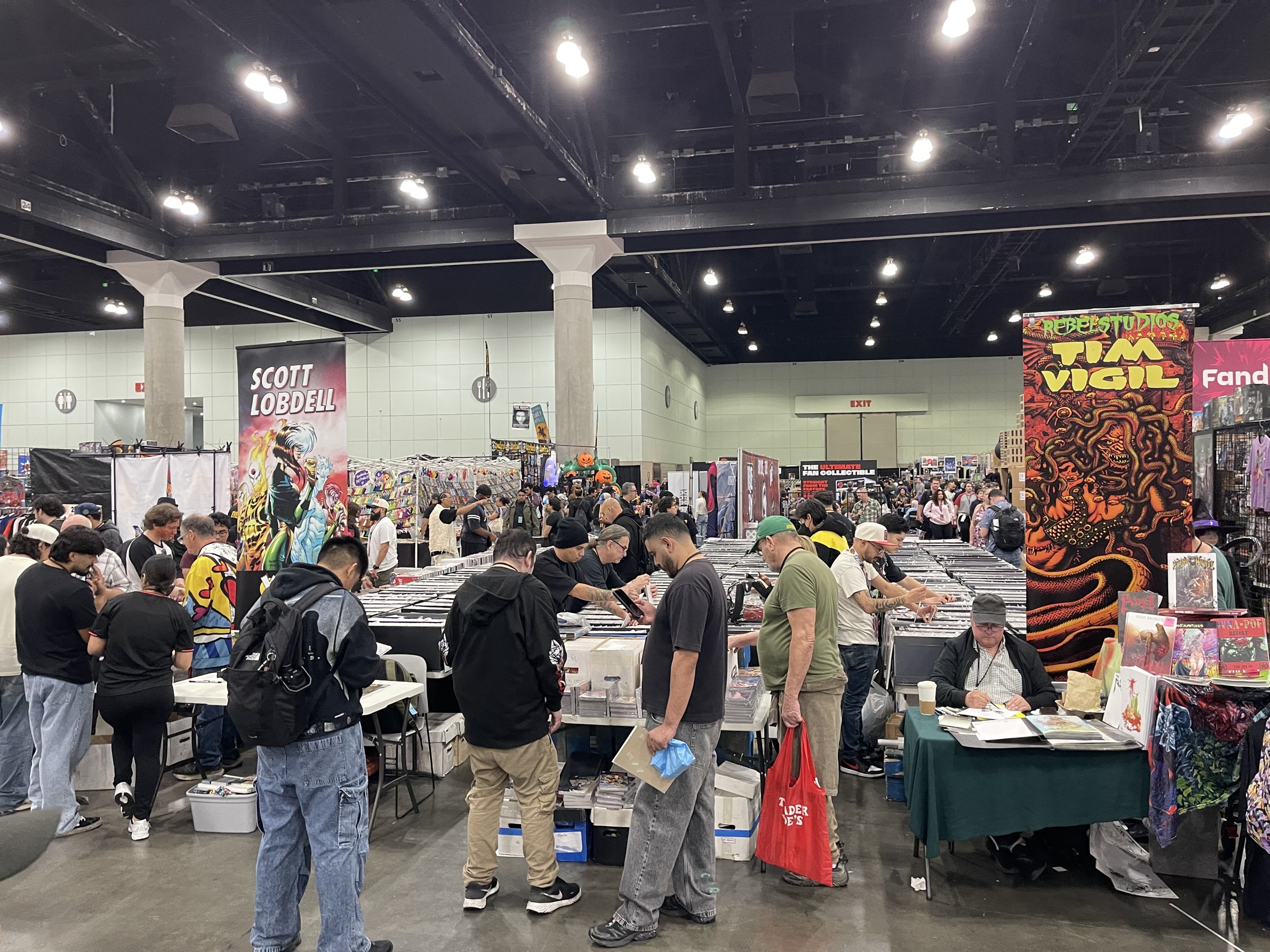 Fans dig through long boxes of comics between Scott Lobdell and Tim Vigil banners at L.A. Comic Con 2026