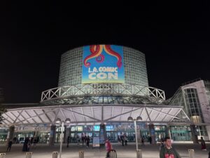 The Los Angeles Convention Center at night with a giant L.A. Comic Con banner on its glass tower