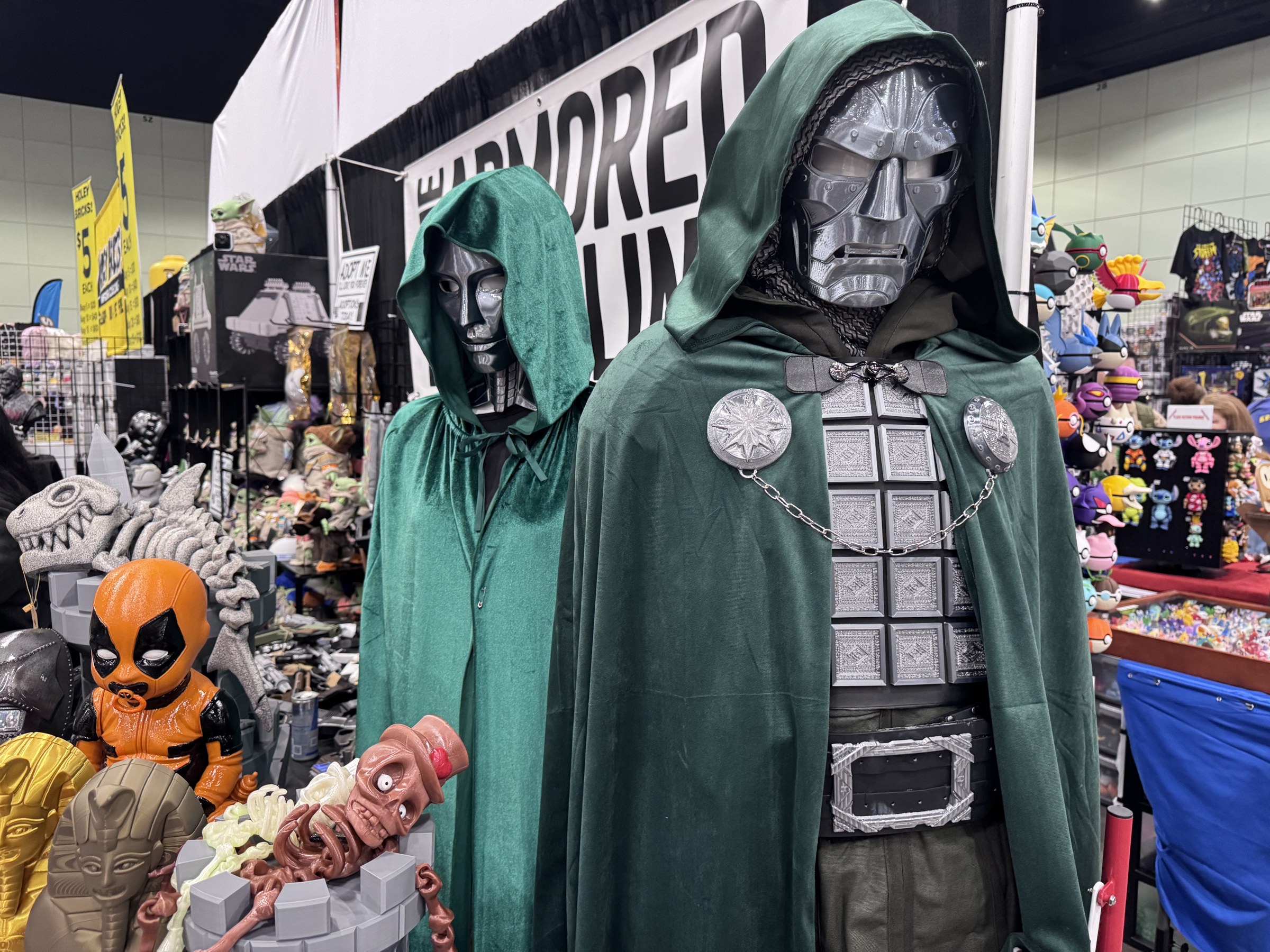 Doctor Doom and Latverian Witch costumes in green hooded cloaks at The Armored Foundling booth