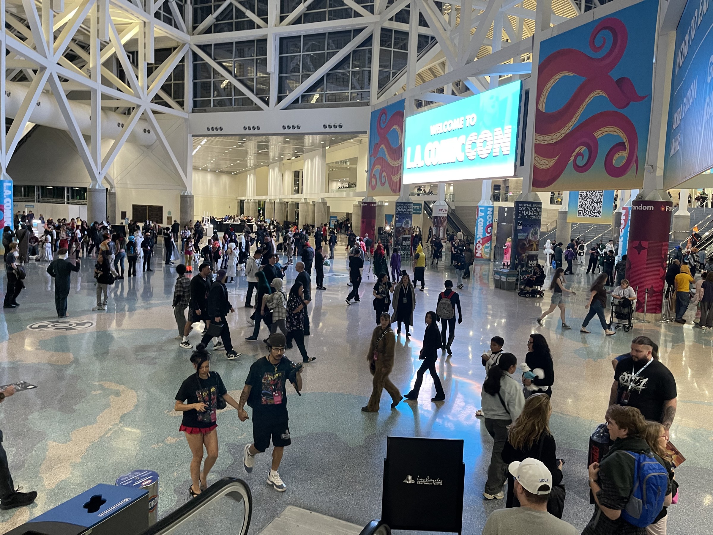 Crowds fill the Los Angeles Convention Center lobby under a Welcome to L.A. Comic Con screen
