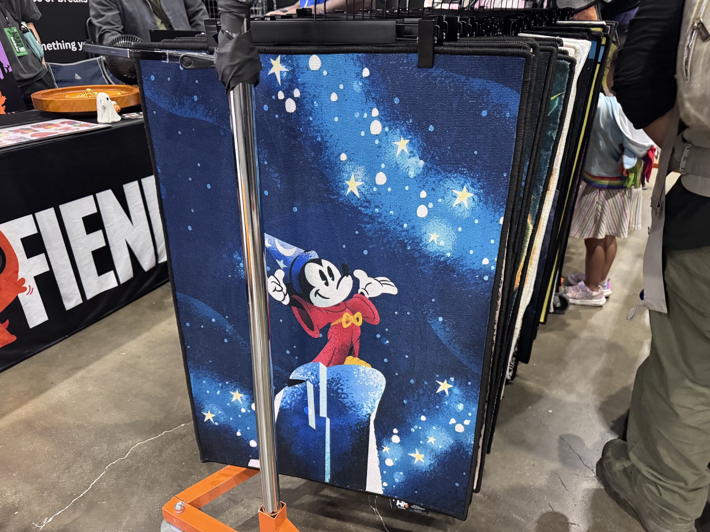 A rug showing Sorcerer Mickey on a starry blue background hanging on a rolling rack
