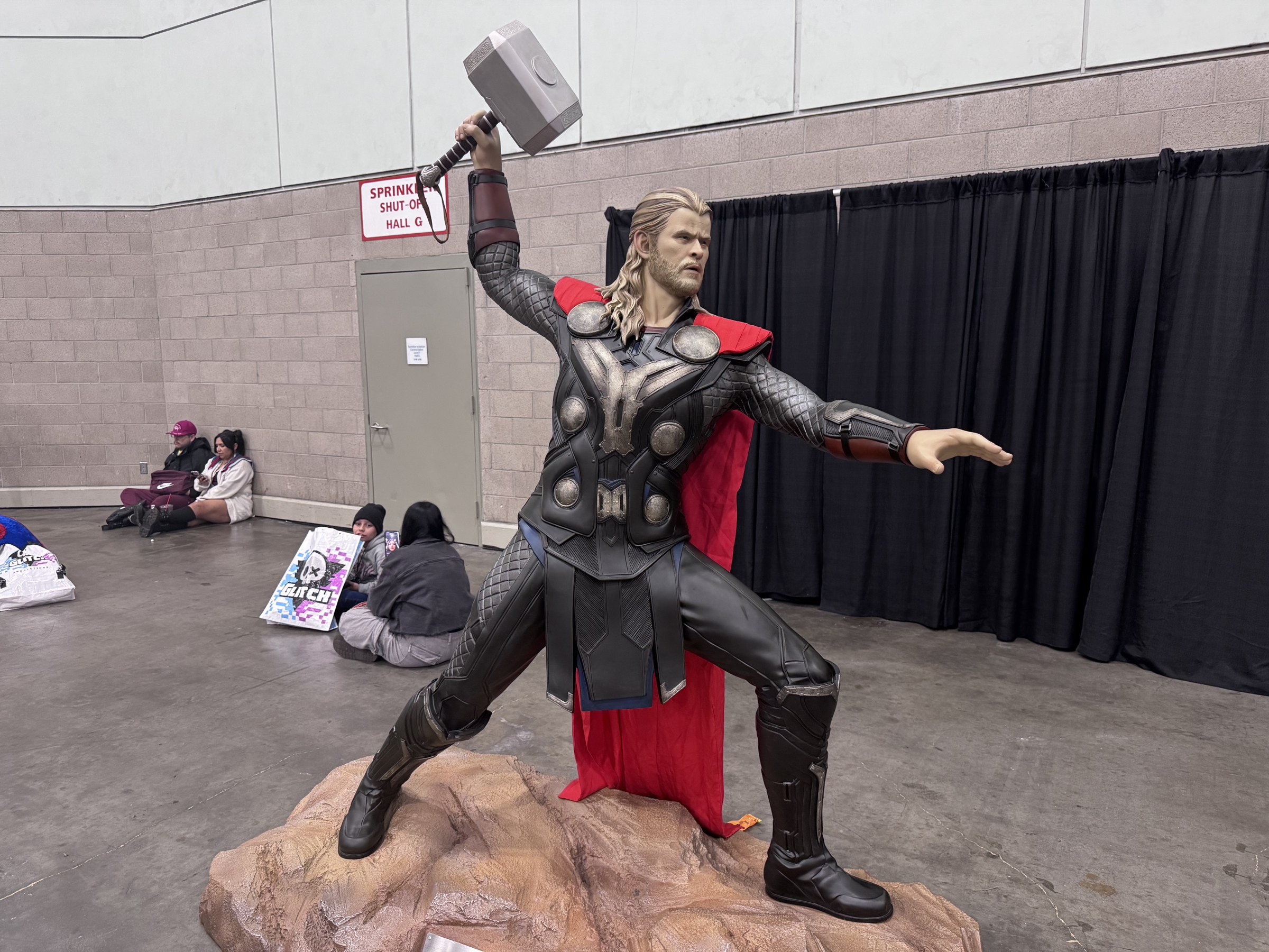 A life-size Thor statue holding his hammer aloft on a rock base at L.A. Comic Con