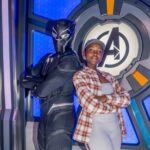 Lupita Nyong'o and Black Panther stand back to back with arms crossed in front of an Avengers logo at Marvel Avengers Campus in Disneyland Paris