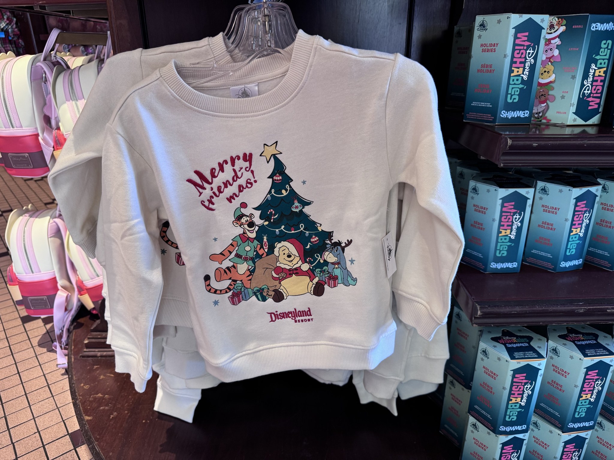 Cream Disneyland Resort sweatshirt reading Merry friend-mas with Tigger as an elf, Santa Pooh and Eeyore in reindeer antlers around a Christmas tree