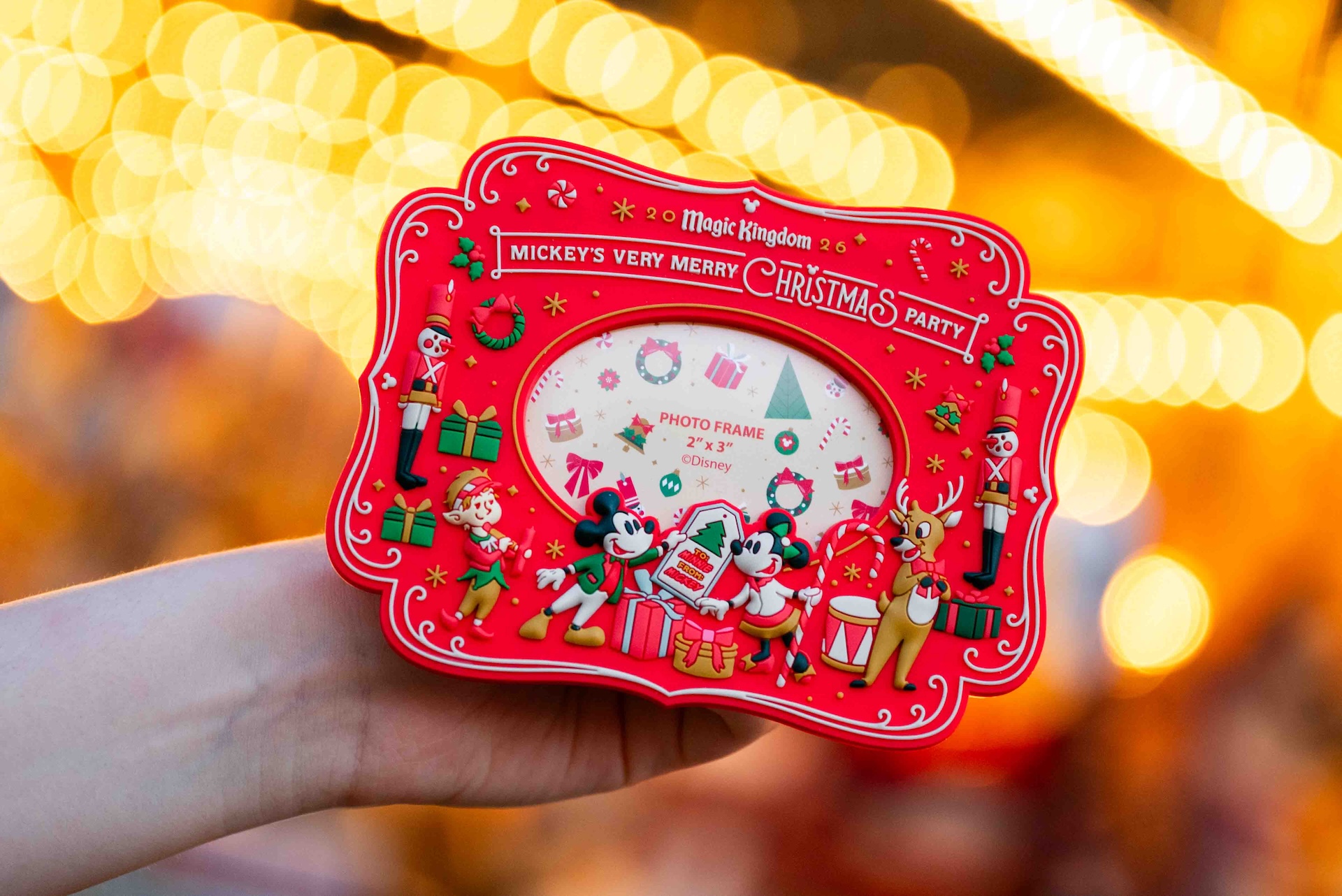 Red Mickey's Very Merry Christmas Party magnet picture frame with a 2 by 3 inch photo window, Mickey Mouse, Minnie Mouse, an elf, a reindeer and toy soldiers