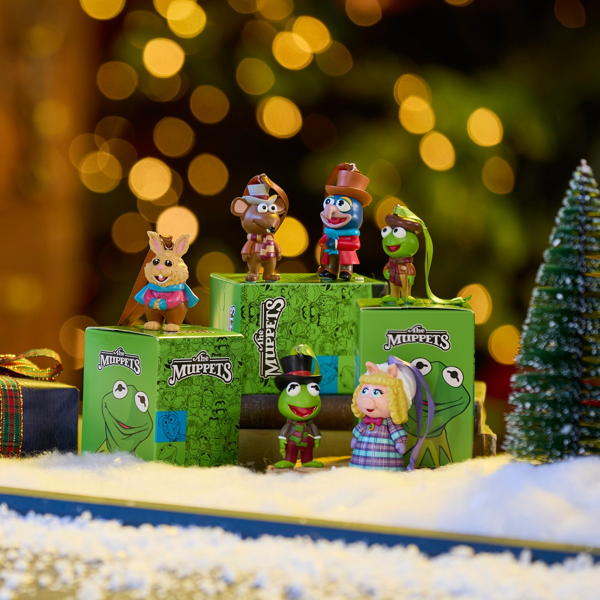 Muppet Christmas Carol blind box ornaments displayed with their boxes in a snowy holiday scene