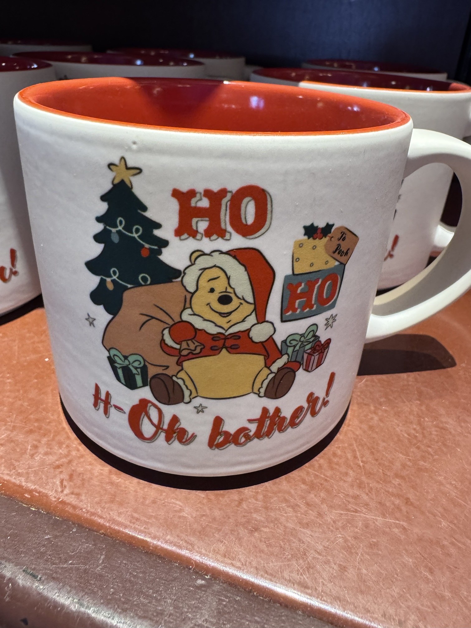 White mug with a red interior showing Pooh dressed as Santa with a toy sack beside a Christmas tree, reading Ho Ho H-Oh bother