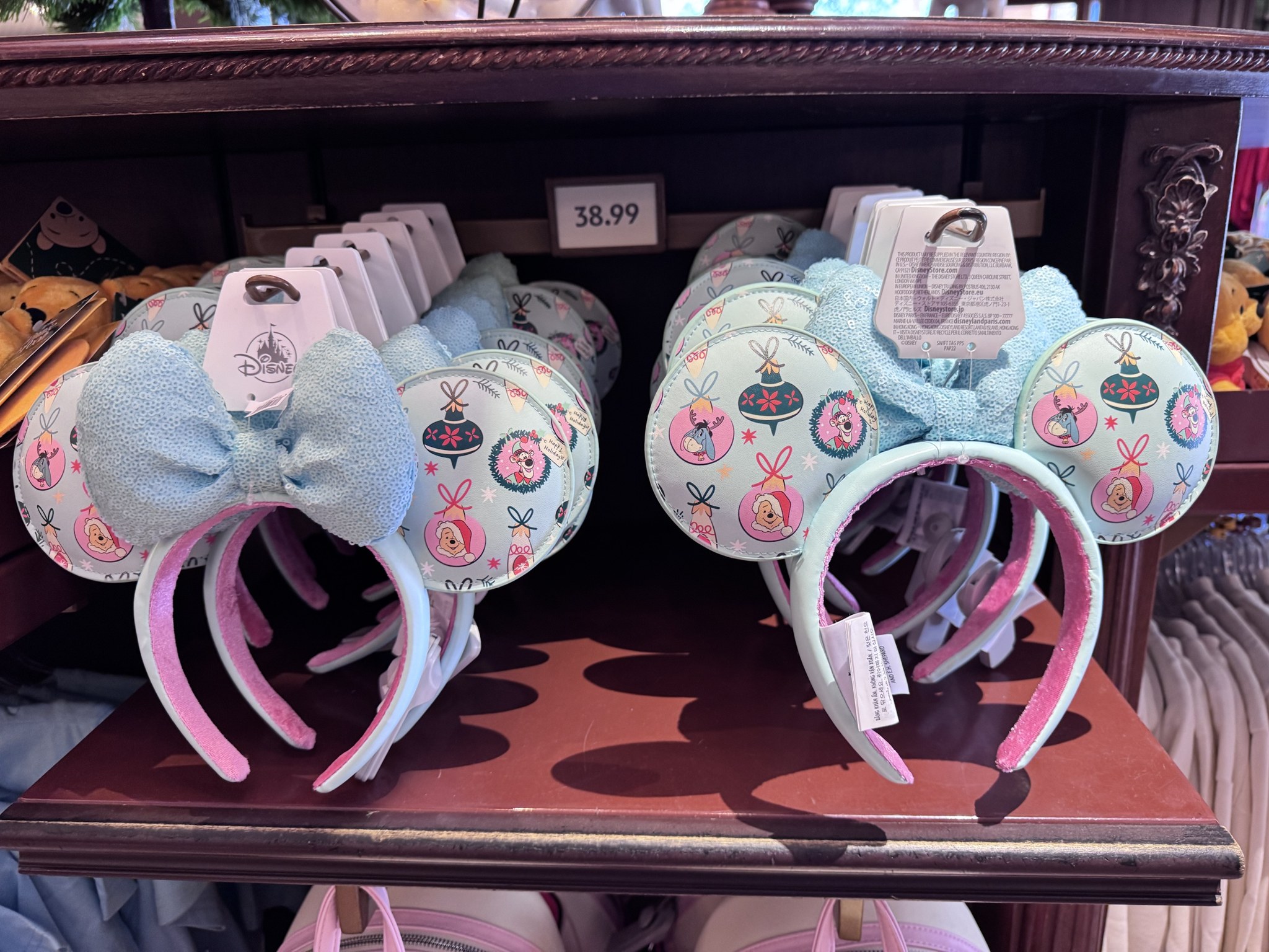Two rows of Pooh holiday ornament Minnie ears on a shelf at the Emporium under a 38.99 price sign