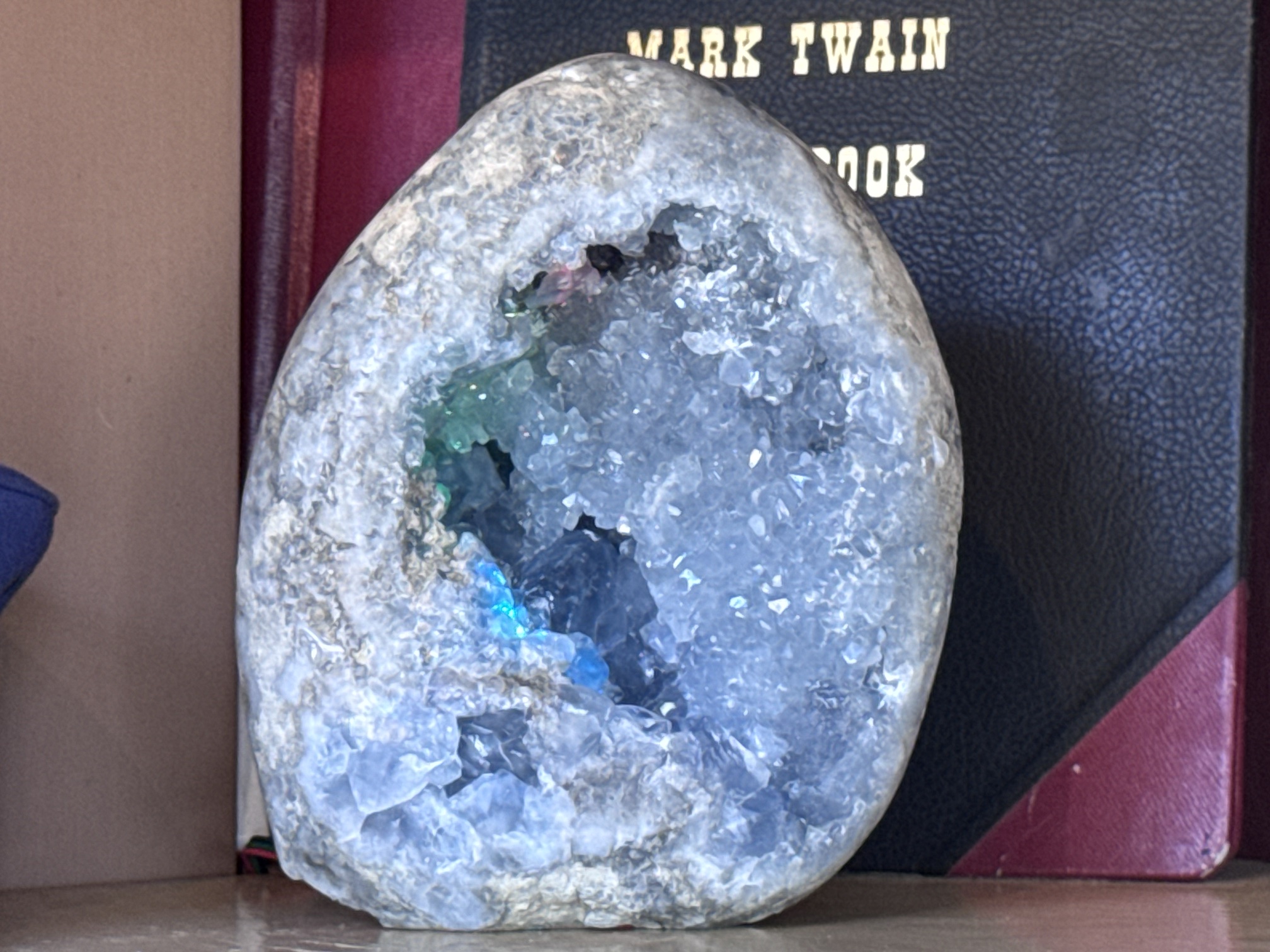 Close-up of the Rainbow Ridge Jewel geode with pink and green light glowing inside its crystal cavity