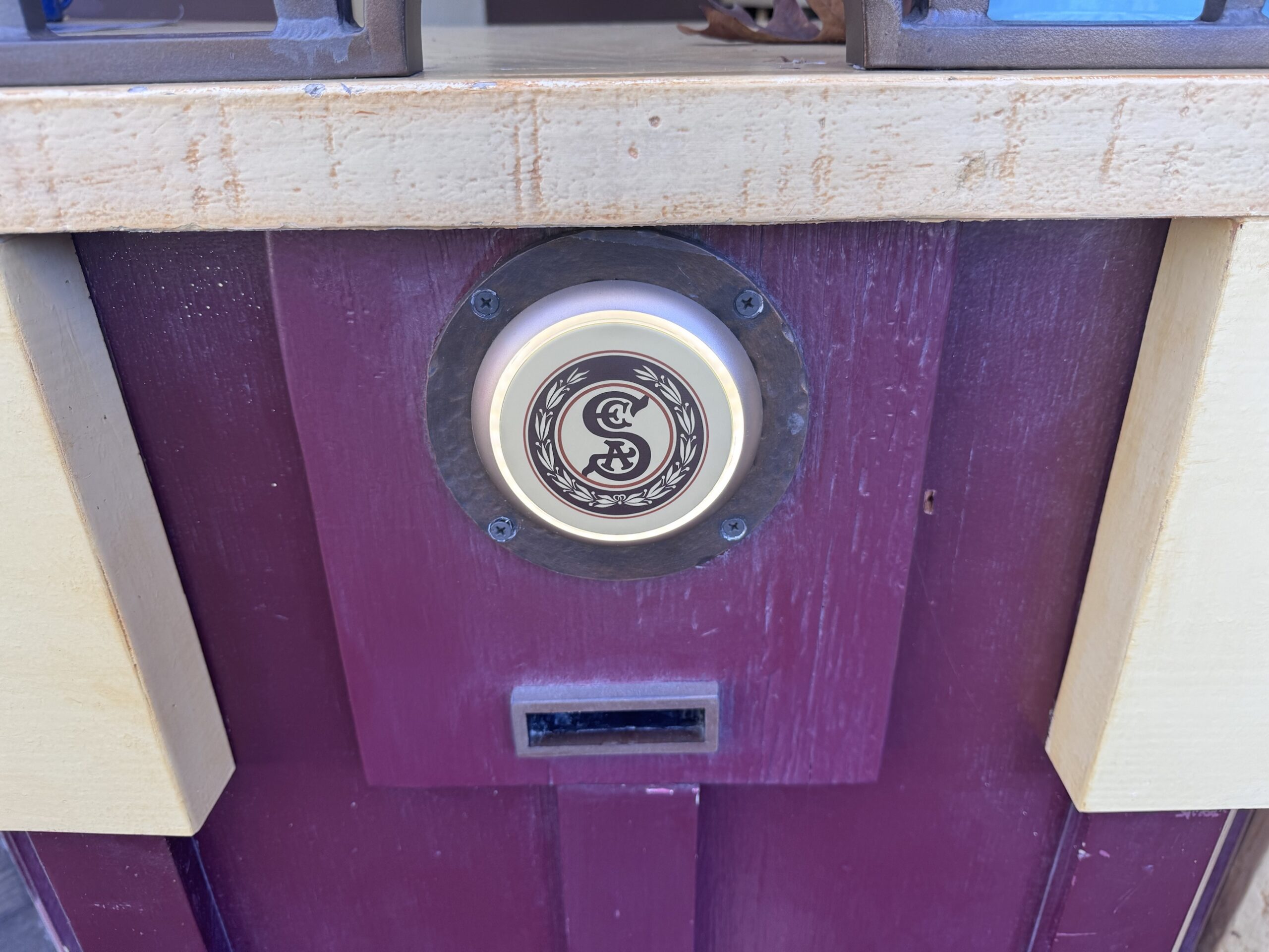 Glowing S.E.A. crest tap point above a ticket slot on the maroon Ticket Booth in Frontierland