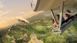 Guests in a suspended Soarin' ride vehicle with their feet dangling above a projected view of the Great Wall of China