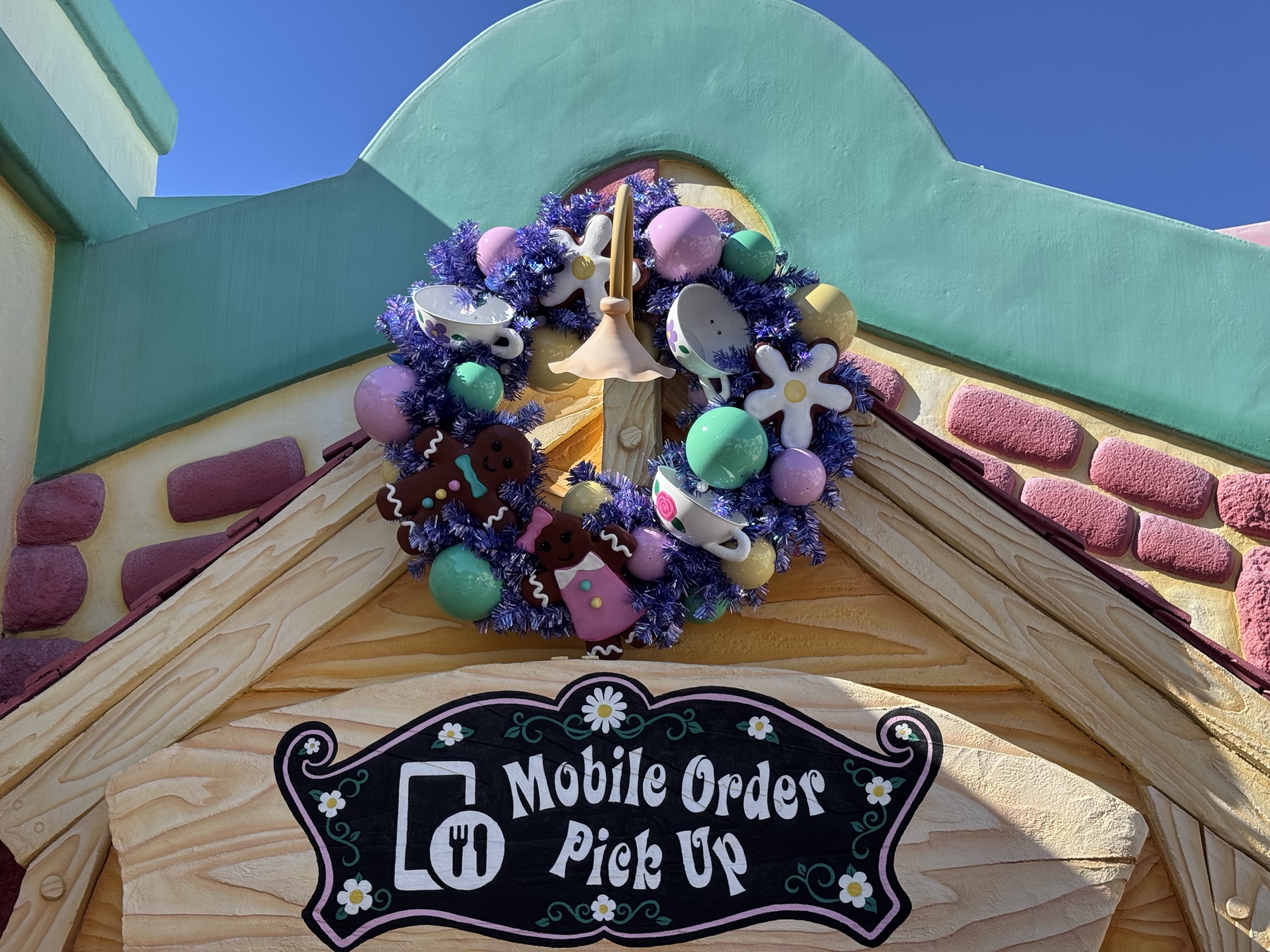 Gingerbread and teacup Christmas wreath over the mobile order pick up window at Cafe Daisy in Toontown