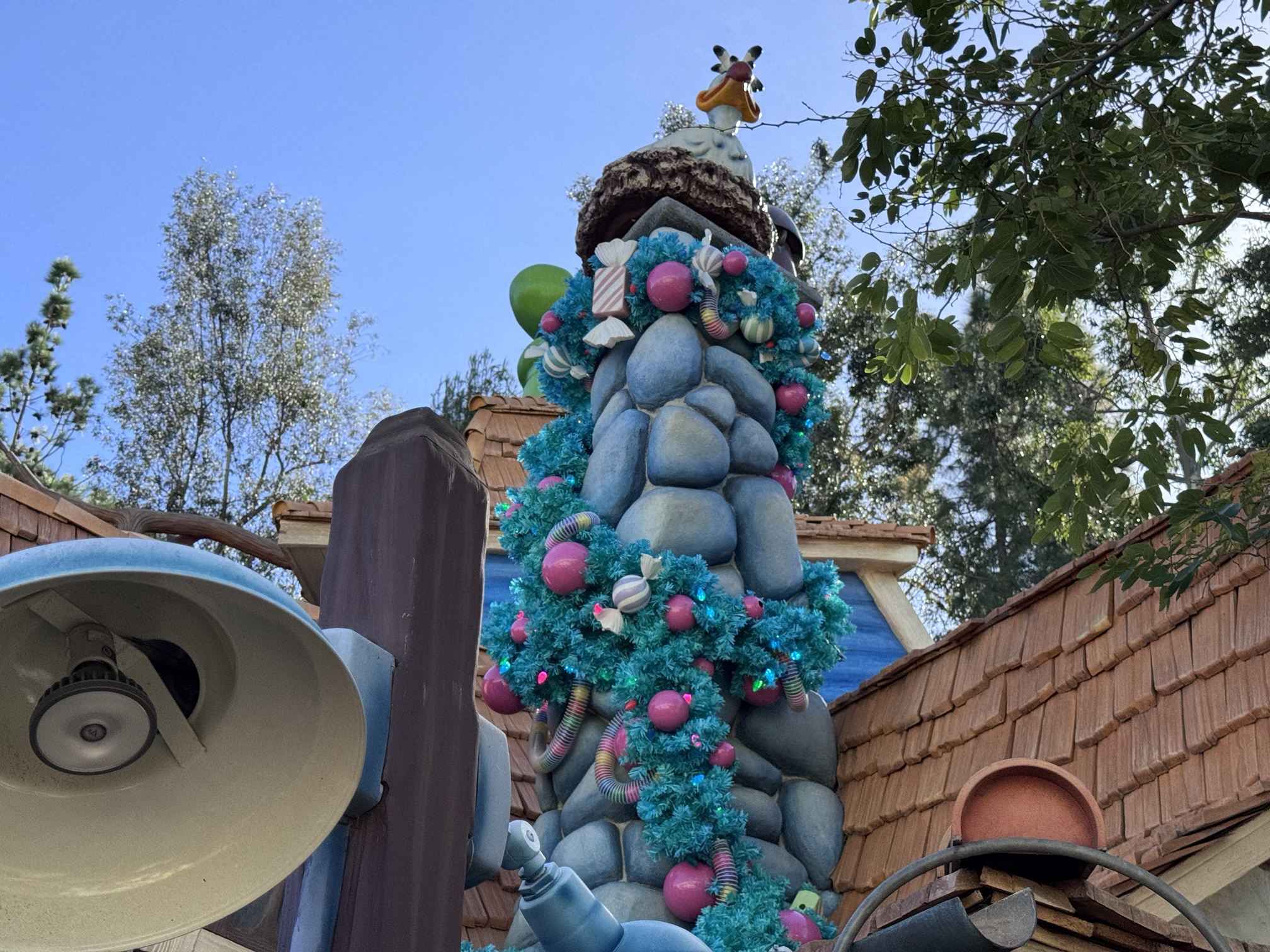 Teal garland with candy and pink ornaments wrapped around a chimney at Goofy's house in Toontown