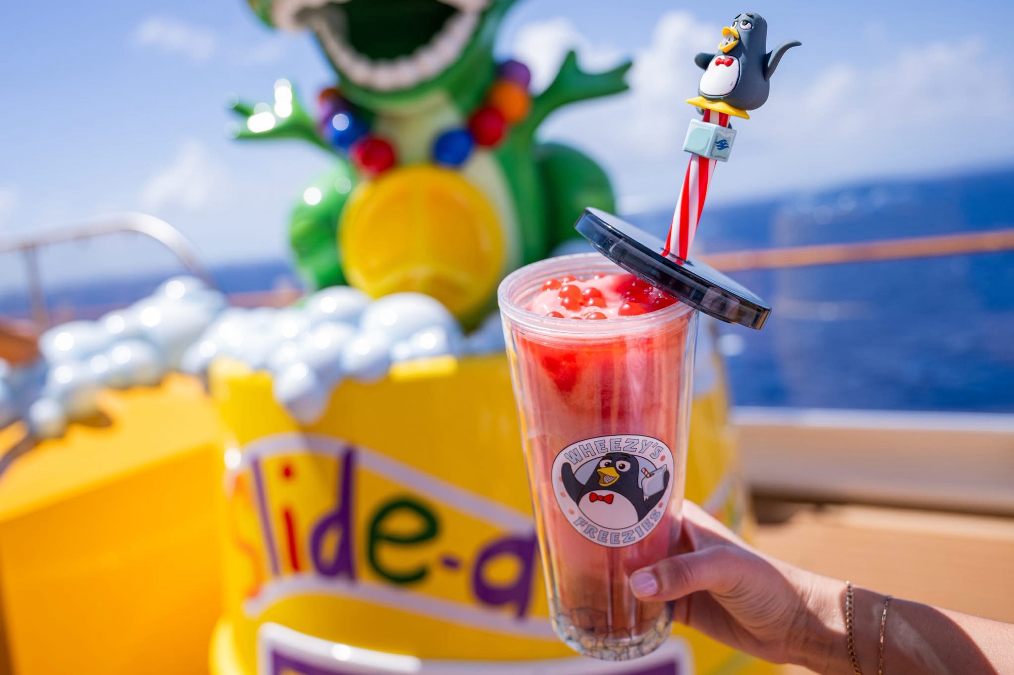 A Wheezy's Freezies boba drink with a Wheezy penguin straw topper on a Disney Cruise Line ship